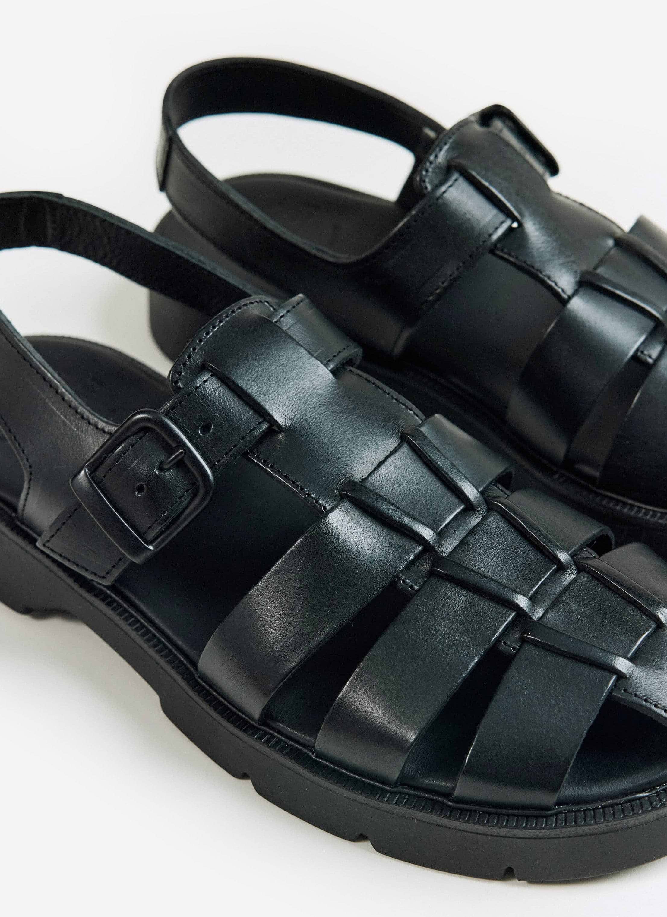 A close-up of the black Kleman Babord VGT leather fisherman sandals from Percival, showing the buckle and woven straps.