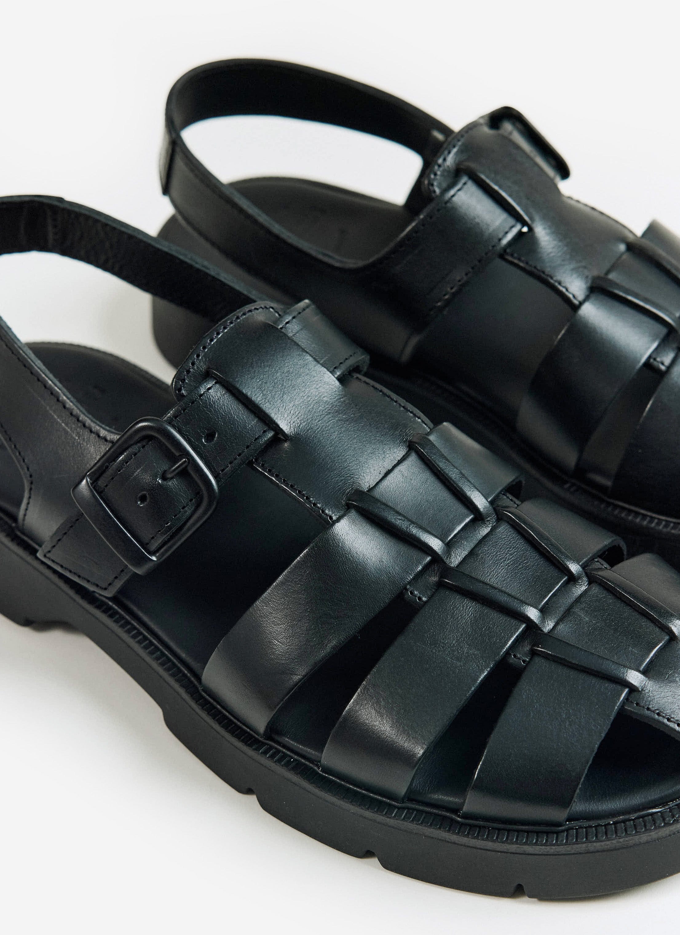 A close-up of the black Kleman Babord VGT leather fisherman sandals from Percival, showing the buckle and woven straps.
