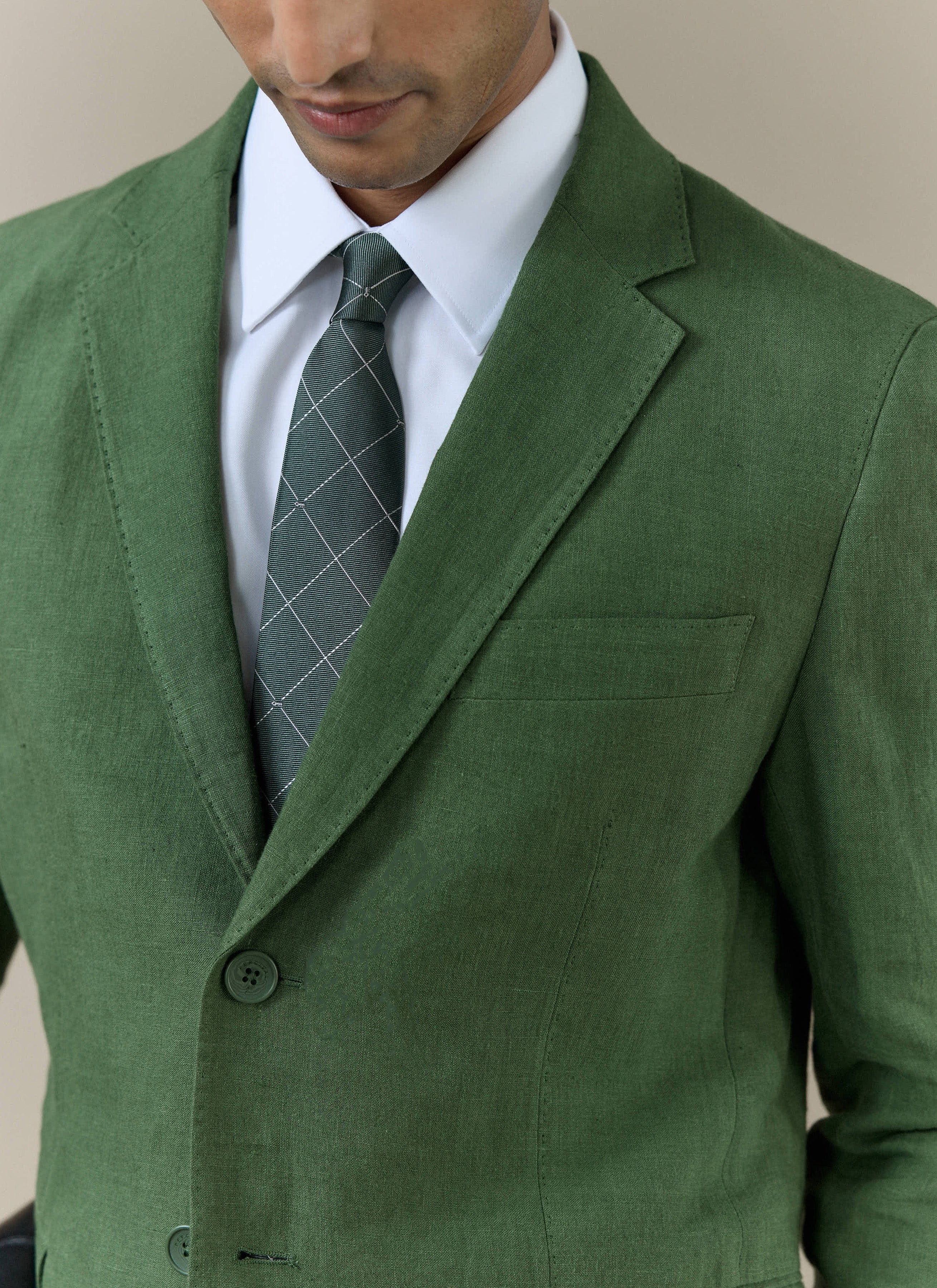 Model wearing the forest green silk Window Pane Key Jacquard Tie by Percival, styled with a matching green linen suit.