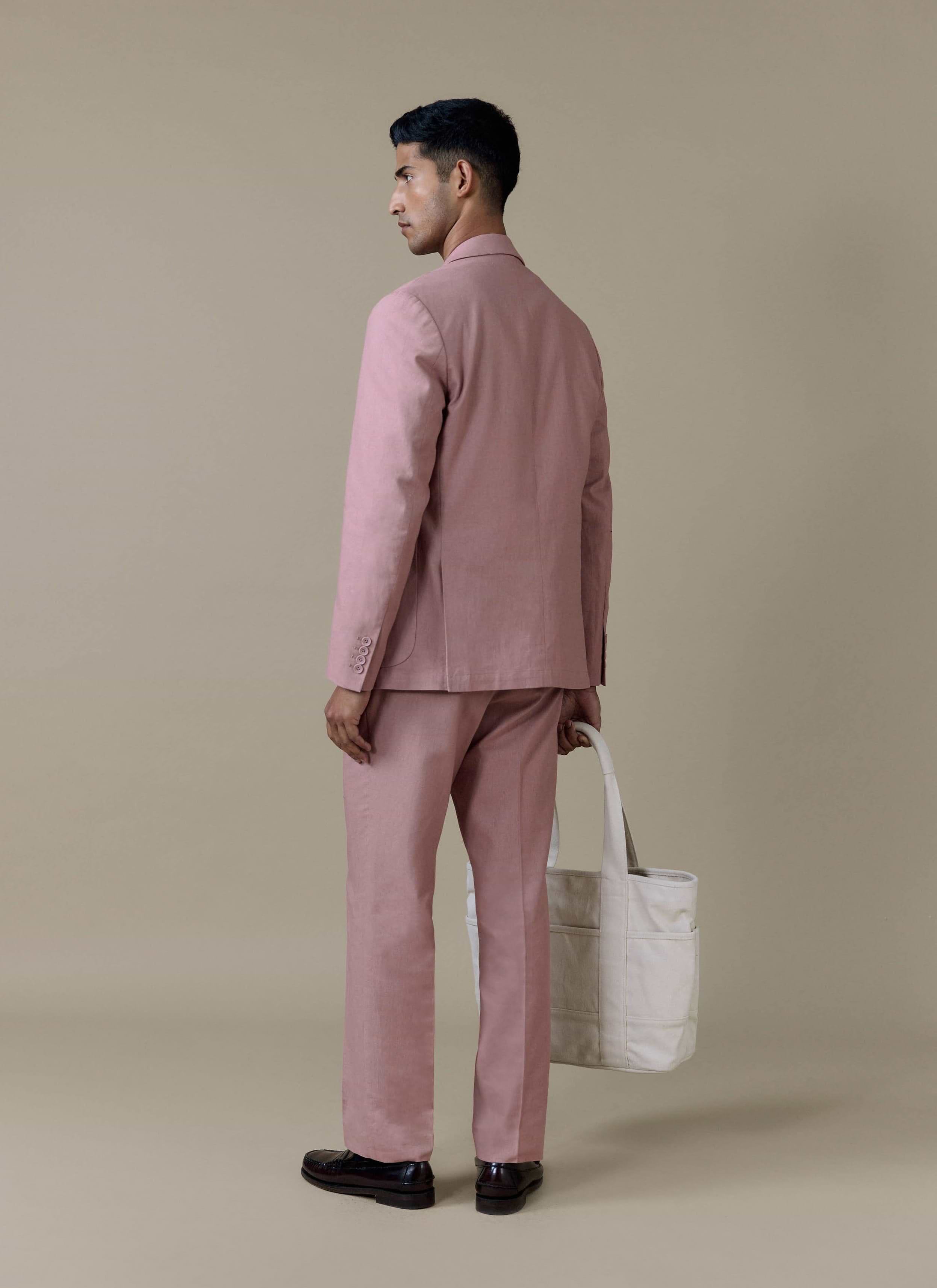 Rear view of the Percival tailored linen blazer and matching suit trousers in dusty pink, styled with a cream tote bag.