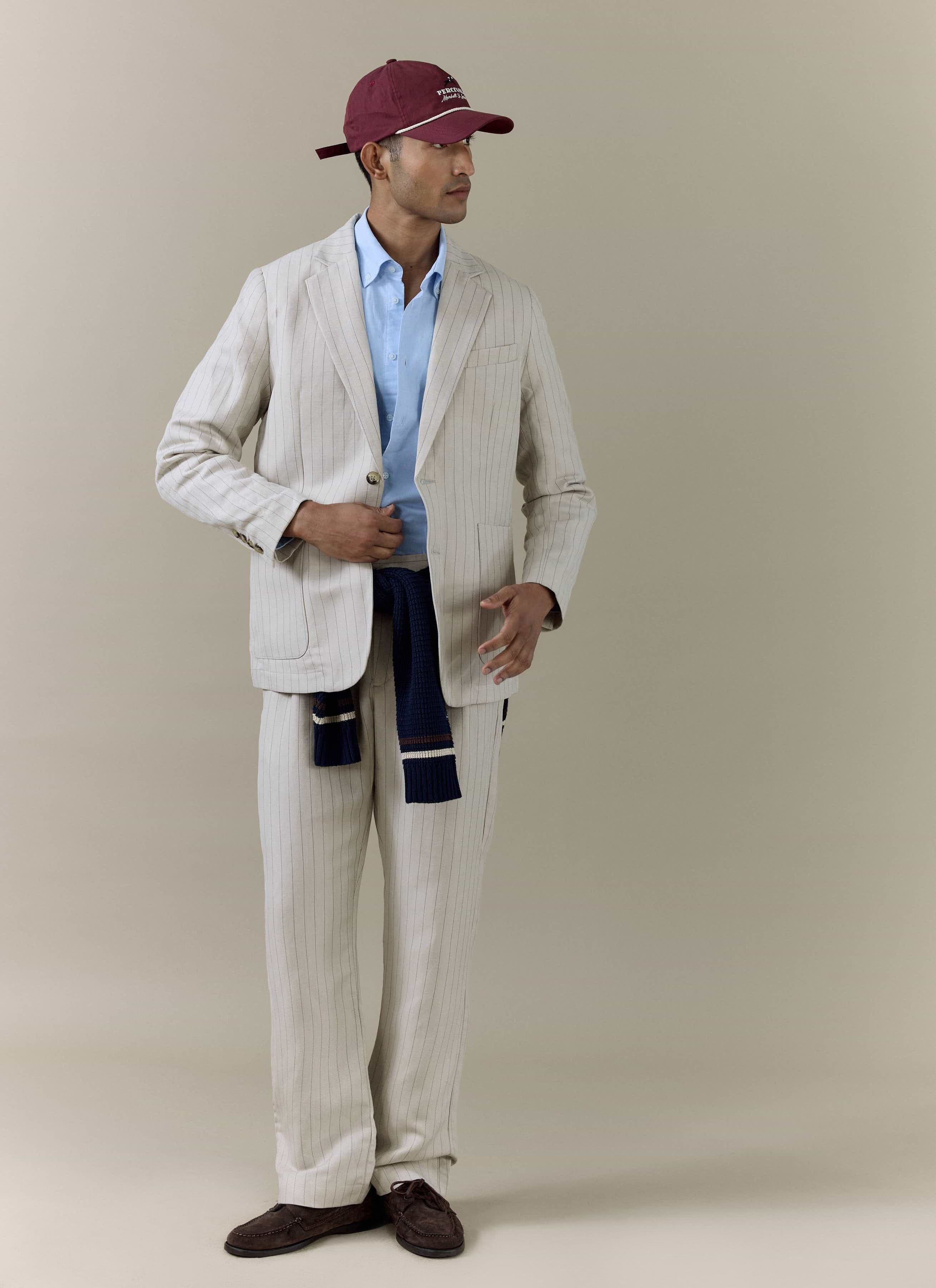 Percival cream striped linen blend blazer and matching trousers, styled with a light blue shirt and burgundy cap.
