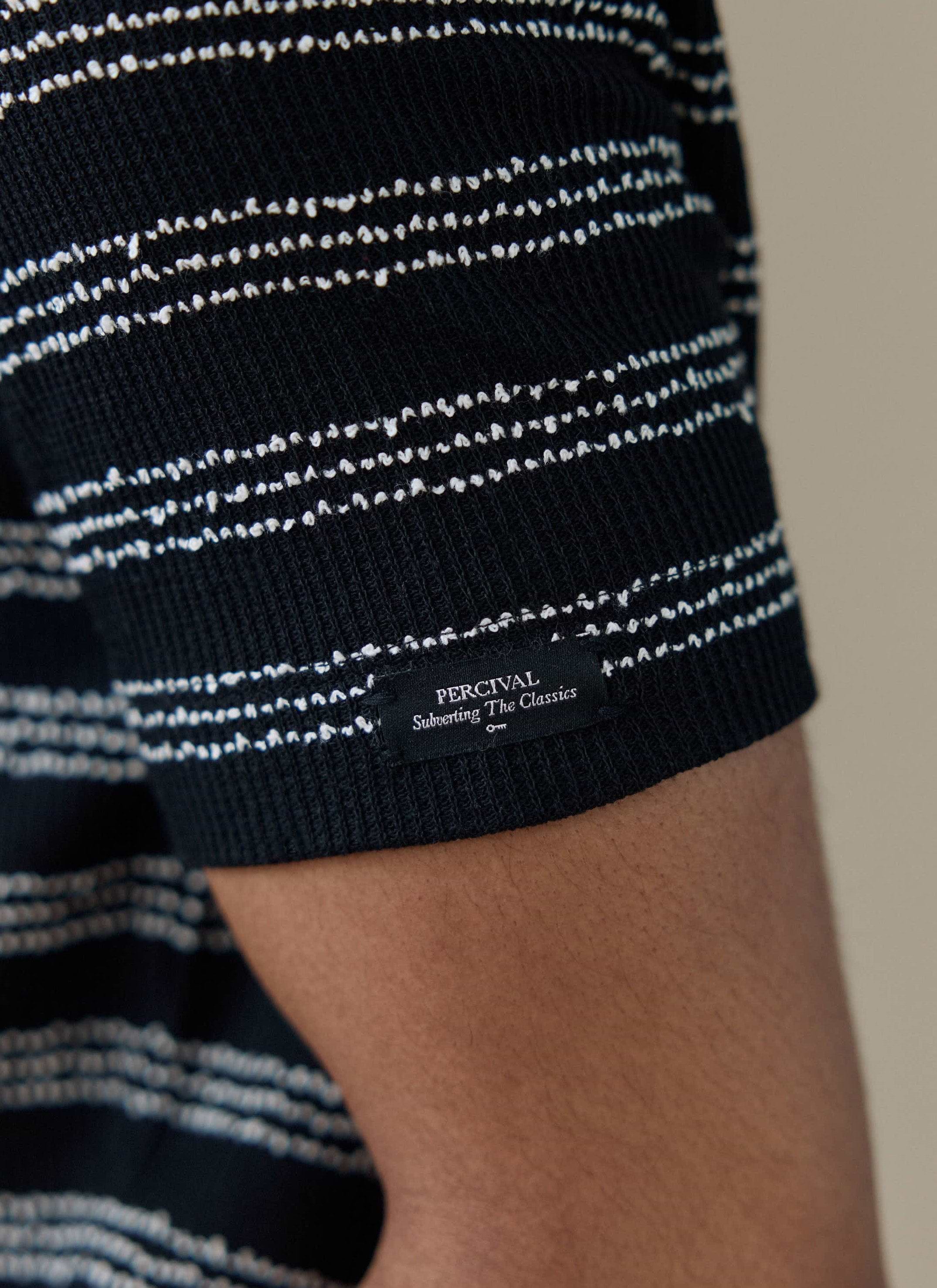 Close-up of the sleeve cuff on the black stripe Percival Laurent Polo, showing the branded woven label.