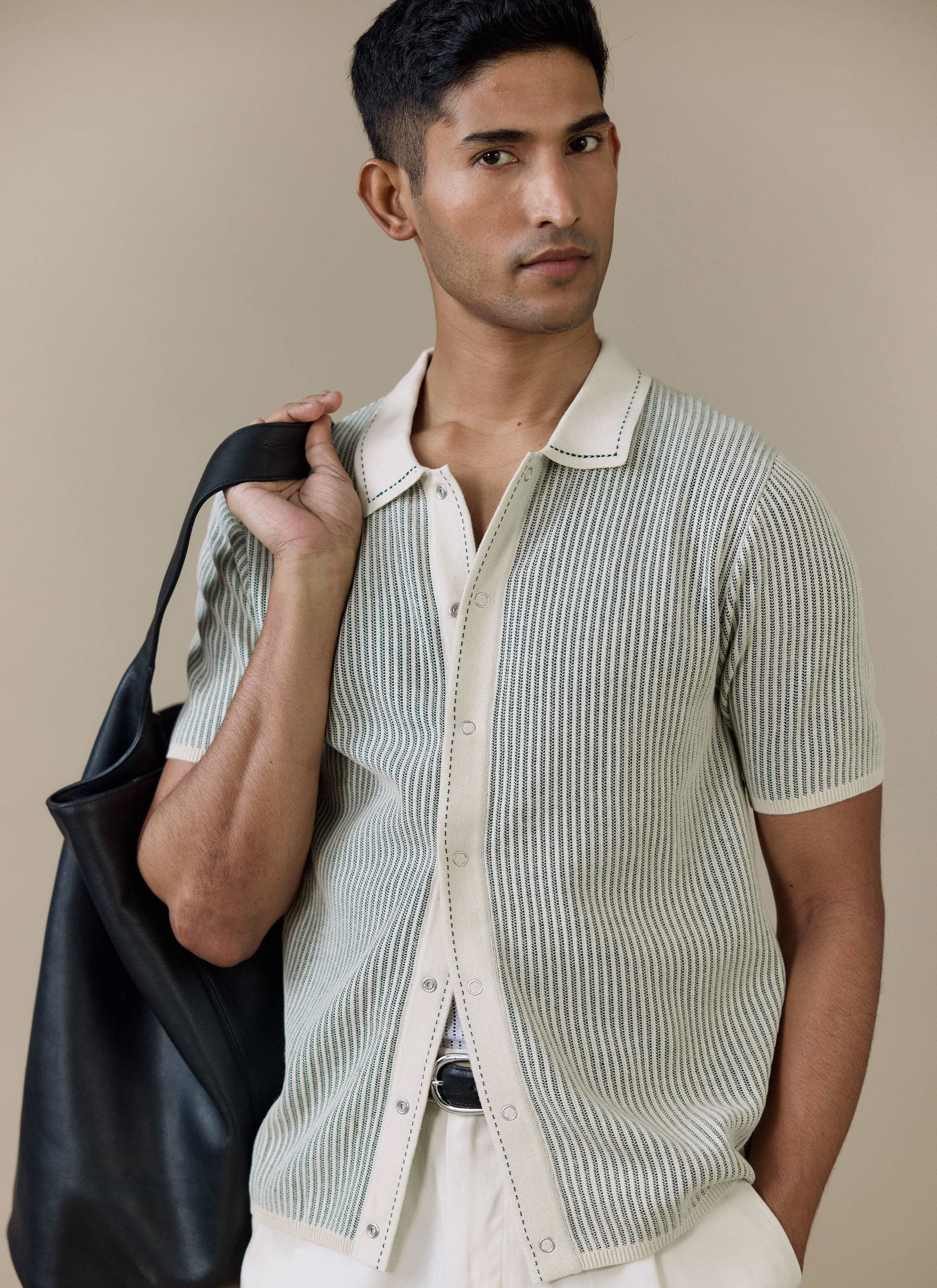 Model wearing the Percival Dixon Knitted Shirt in cream, a button-through cotton polo with vertical stitch detailing.