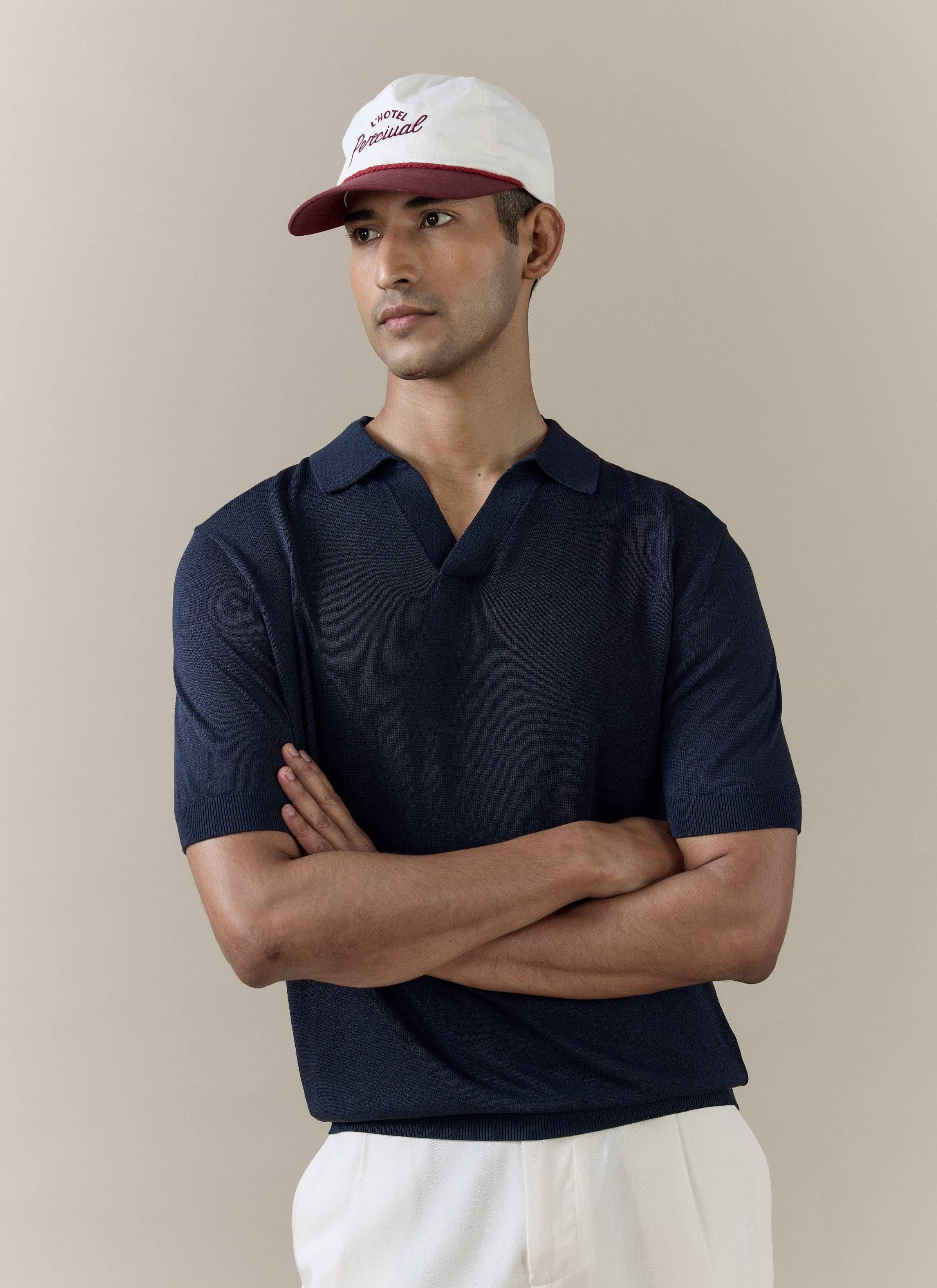A model wears the navy Laurence Knitted Polo by Percival, featuring an open V placket and breathable linen lyocell blend.