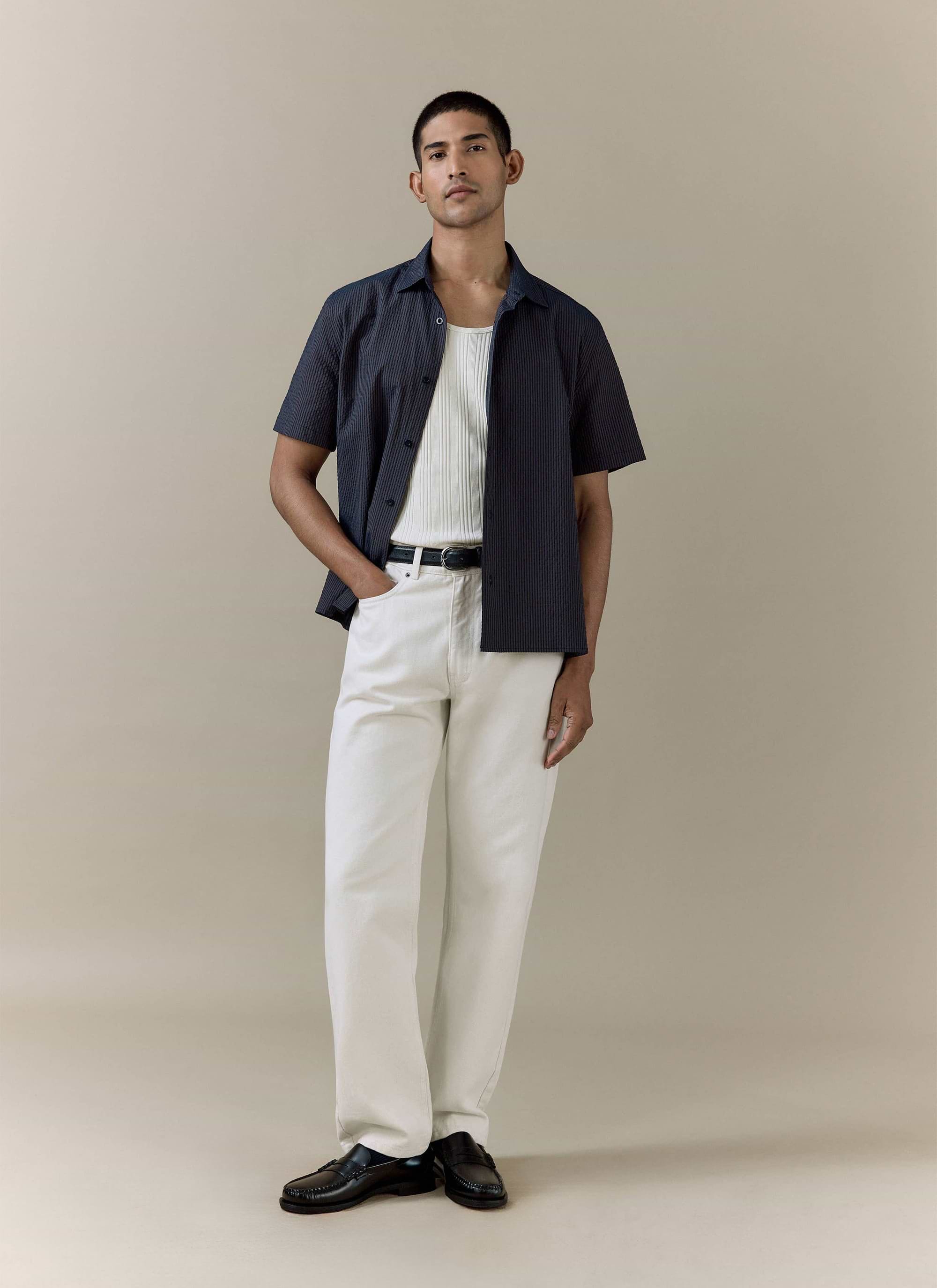 Model wears a Percival navy stripe Rowan Seersucker Boxy Shirt and cream straight leg denim jeans.