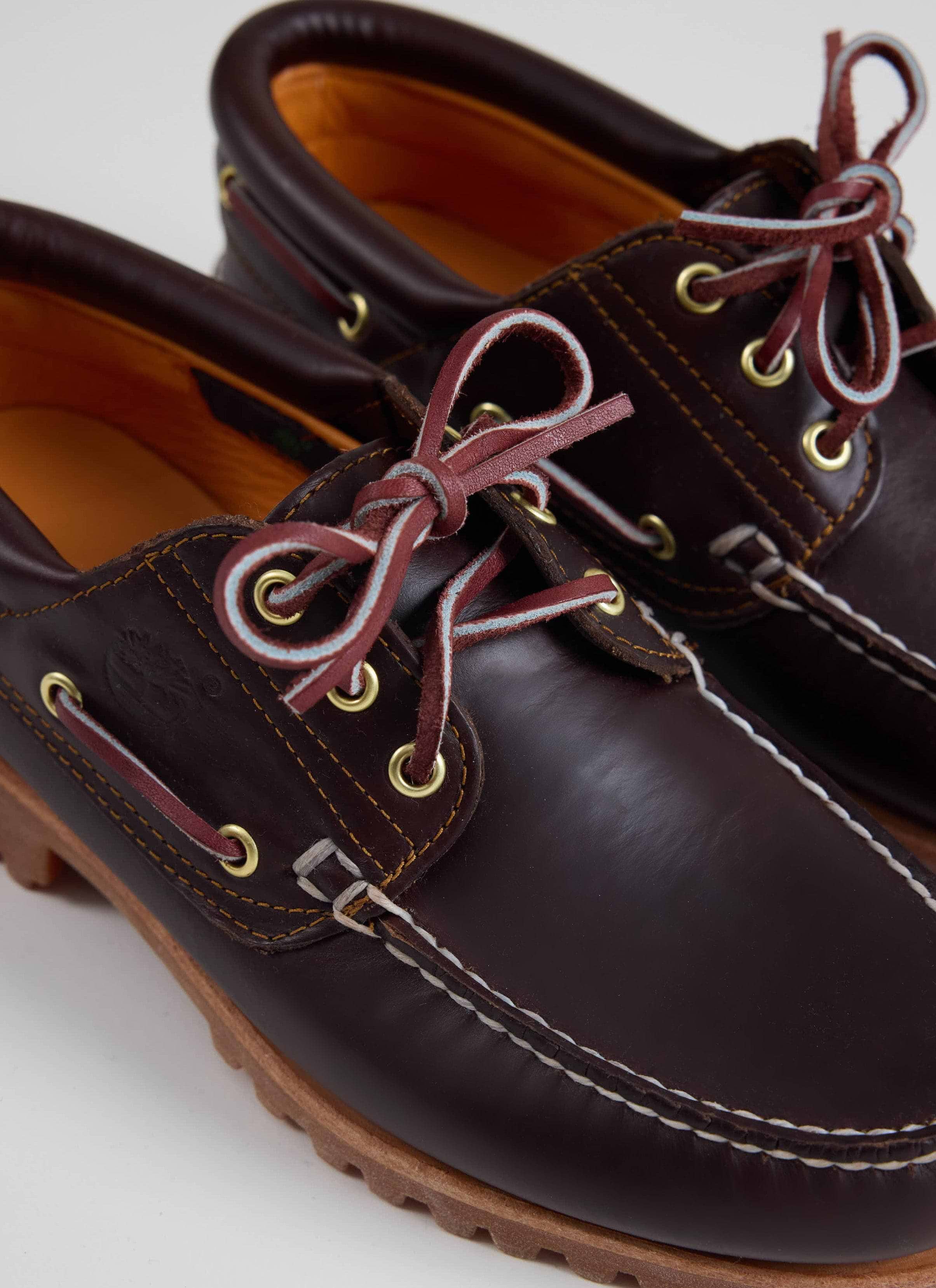 A close-up of the brown leather Timberland Authentic Boat Shoe at Percival, showing the rawhide laces and moc stitching.