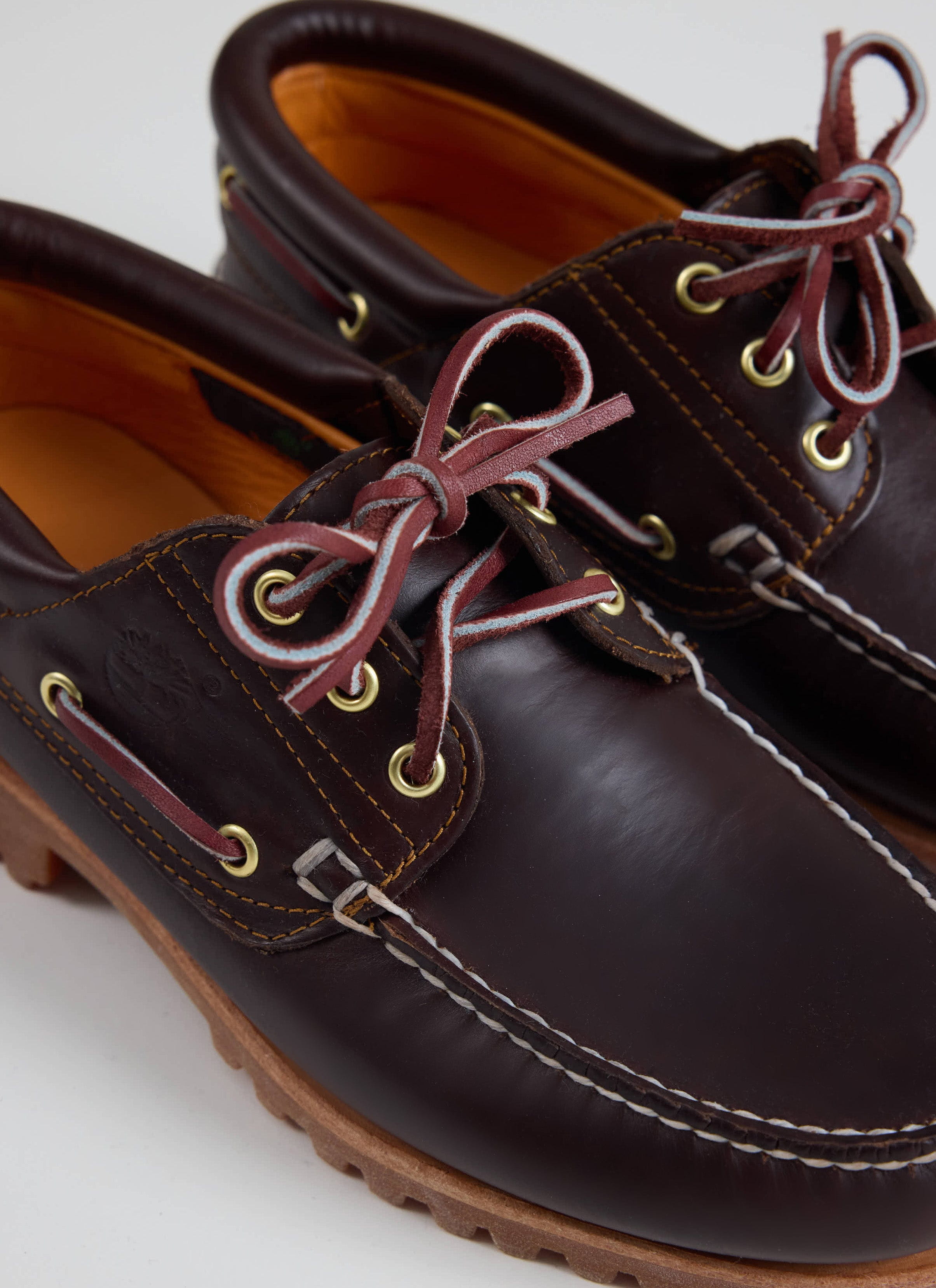 A close-up of the brown leather Timberland Authentic Boat Shoe at Percival, showing the rawhide laces and moc stitching.