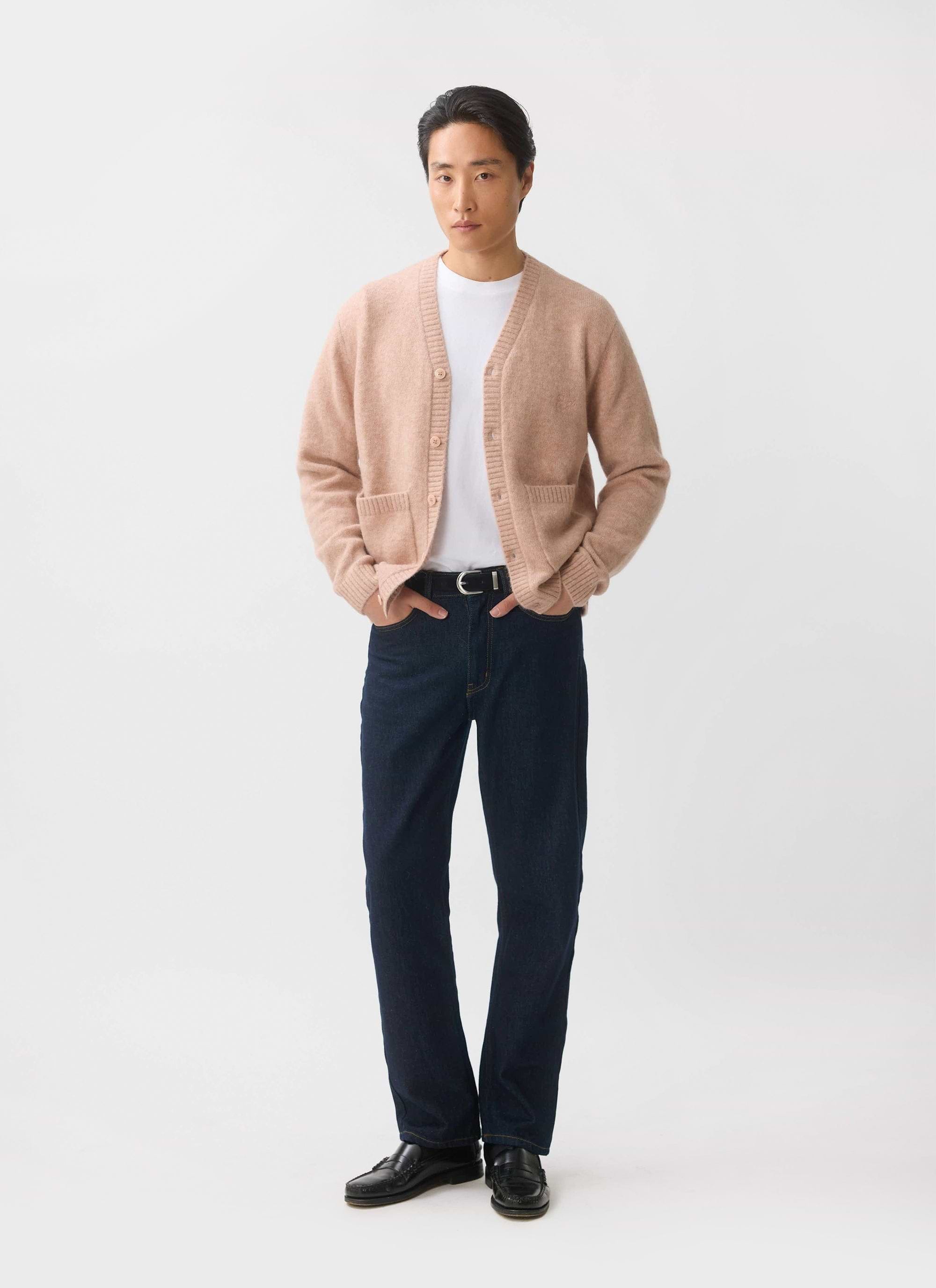 A male model wears the Percival White Glove Cardigan in pink mohair with a white t-shirt and dark blue jeans.