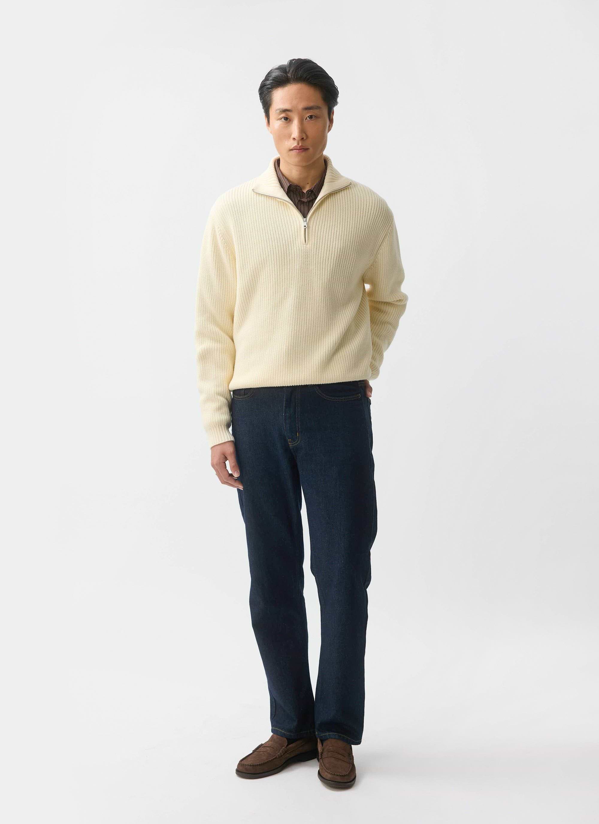 A model wears the Percival Meyer Quarter Zip Fisherman jumper in ecru, styled with dark denim jeans and brown loafers.
