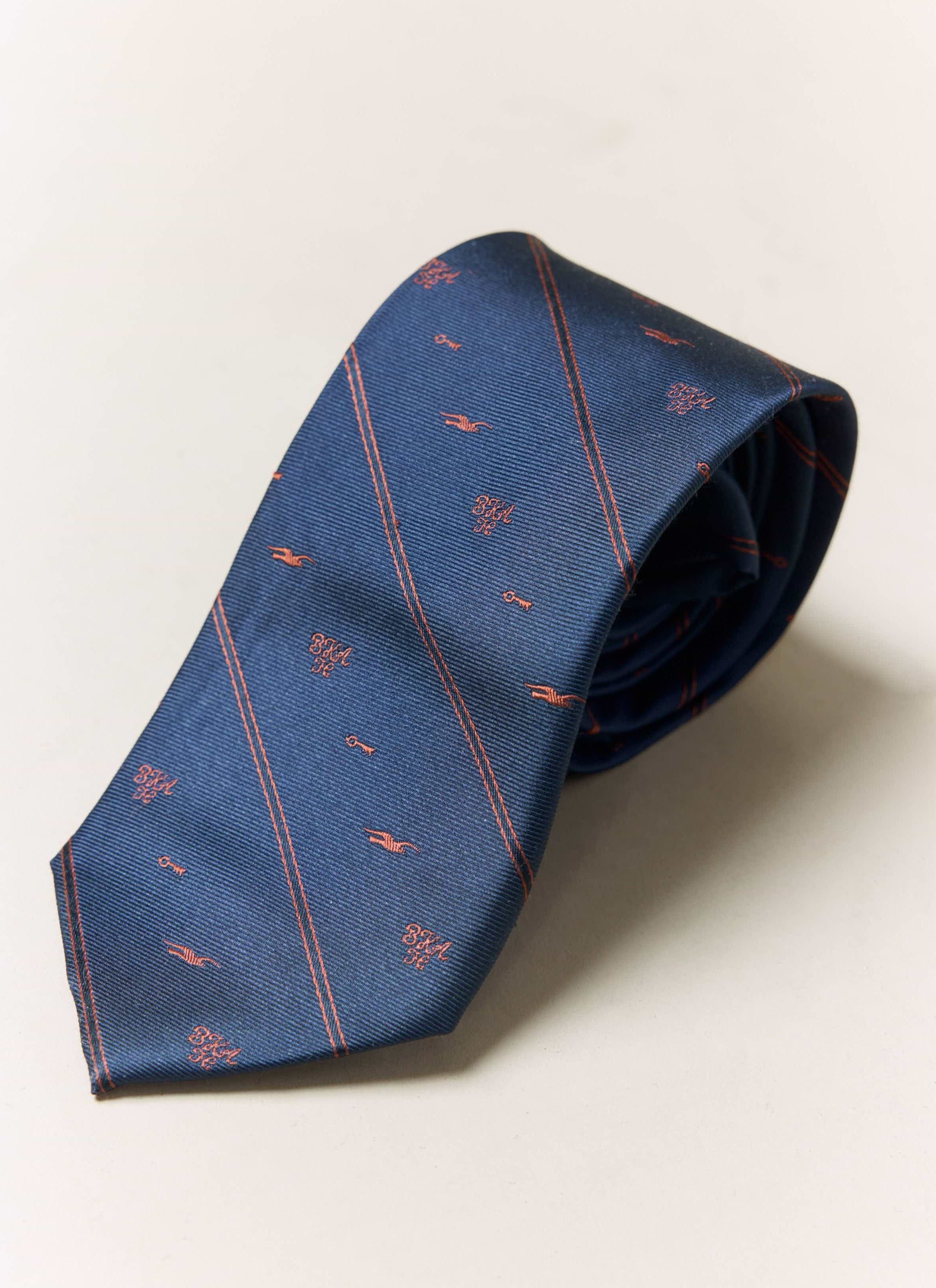 A close-up of the Percival x Brighton & Hove Albion F.C. jacquard stripe tie in navy silk, showing the club motifs.