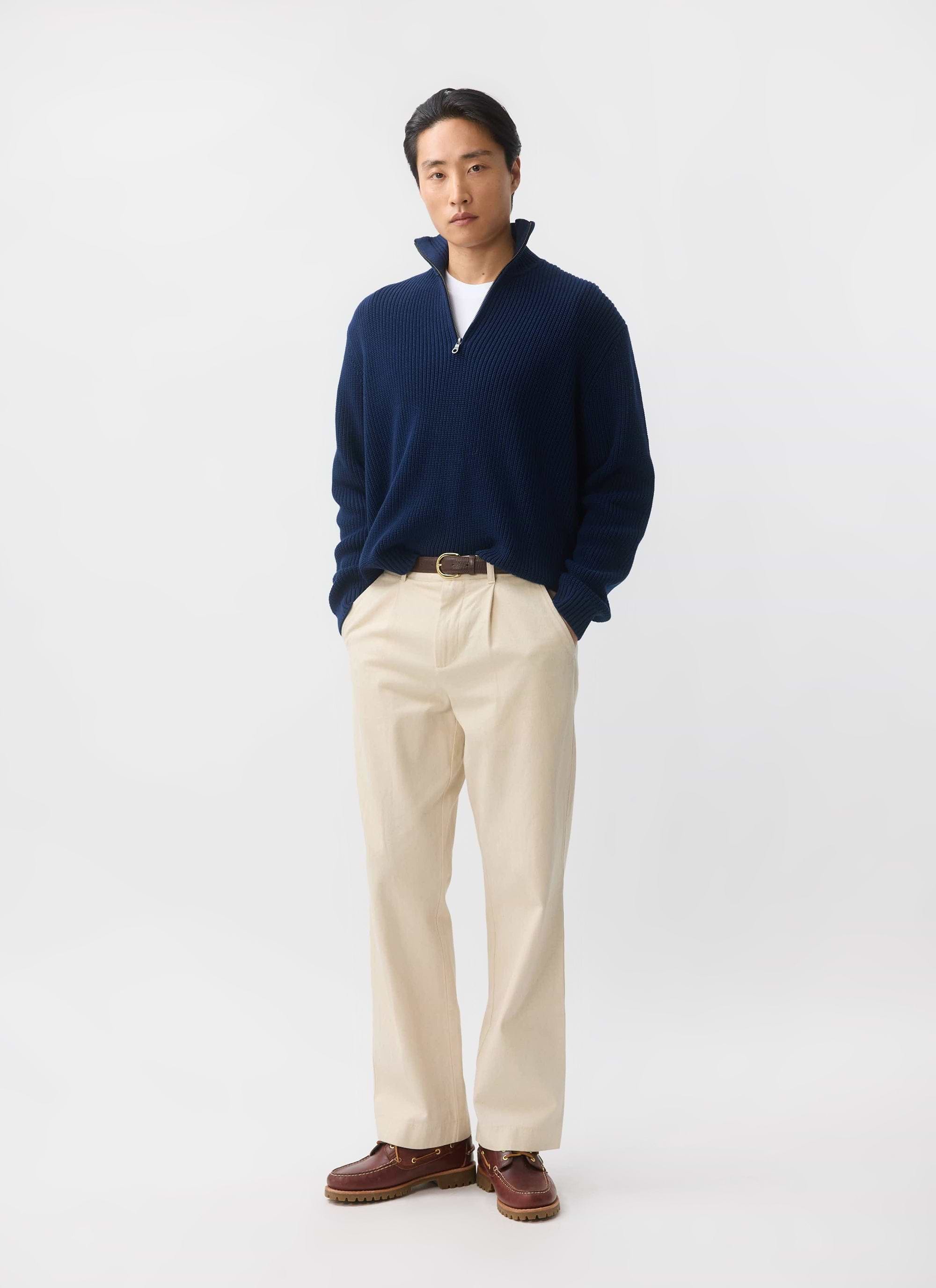 A model wears the Percival Meyer Quarter Zip Fisherman jumper in blue, styled with cream chinos and brown boat shoes.