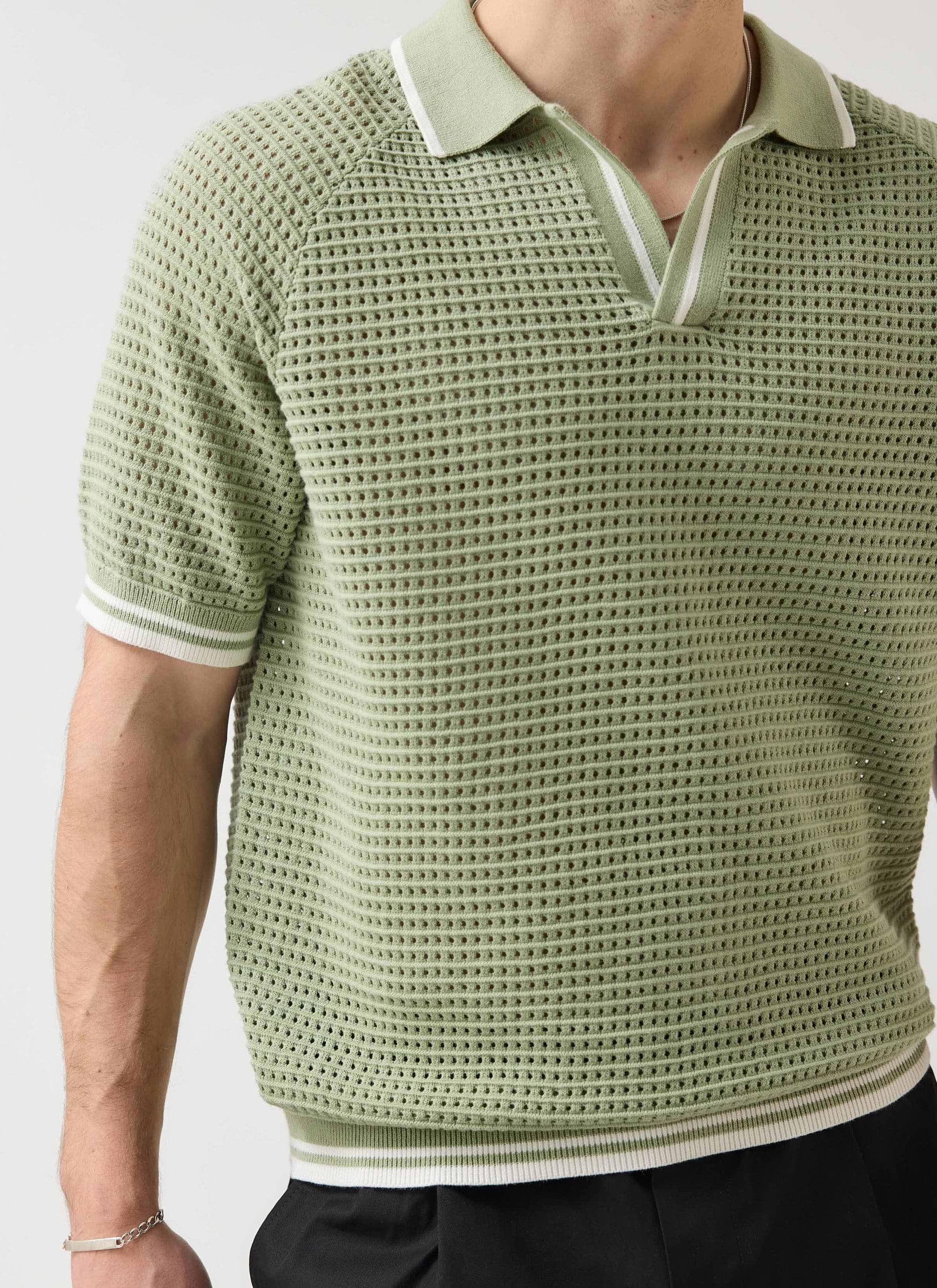 A close-up of the Percival Tennis Boxy Knitted Polo in sage, detailing the perforated cotton knit and striped collar.