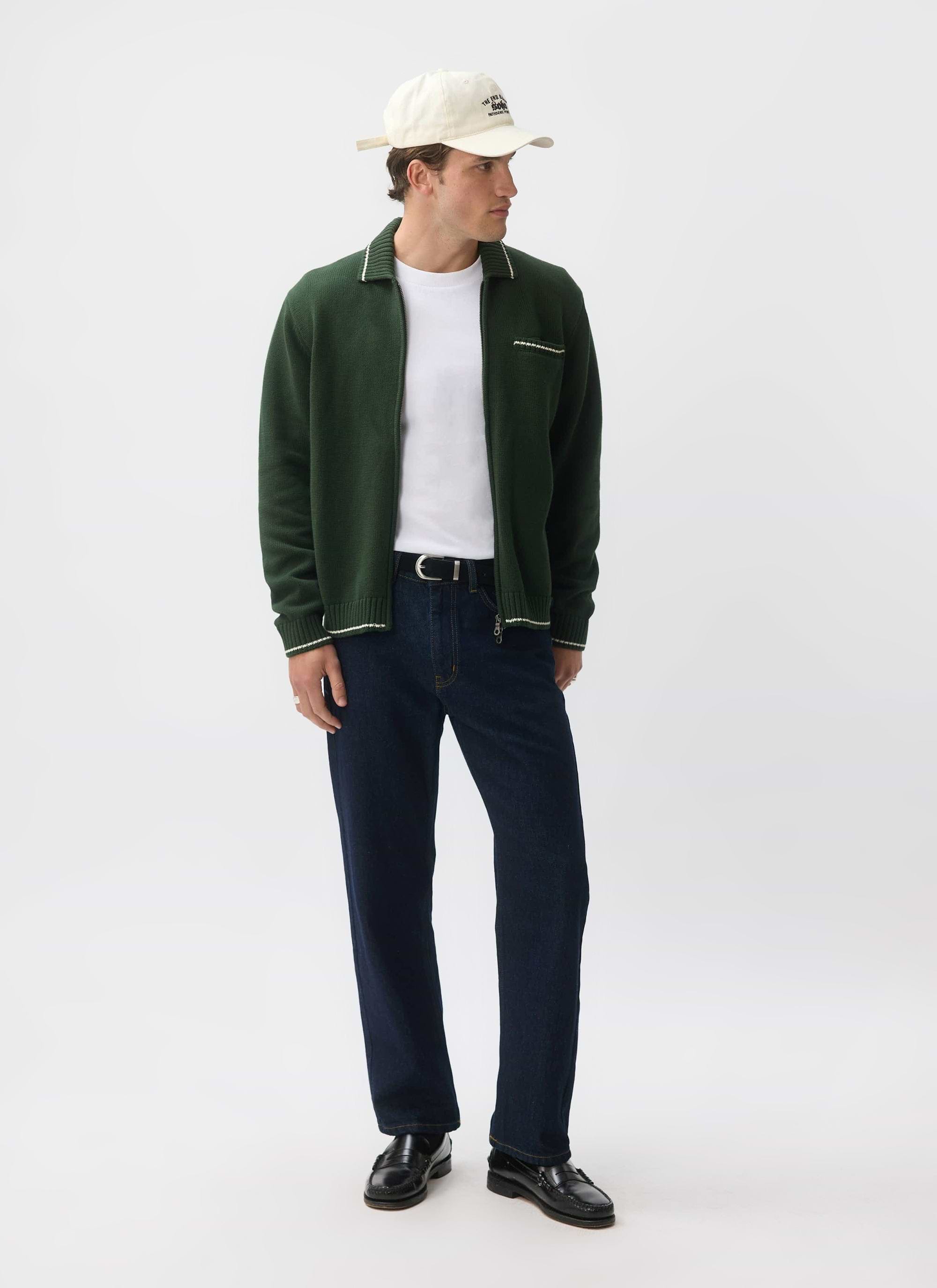 A model wears the Percival Gardner Knitted Zip Cardigan in forest green, styled over a white t-shirt with dark jeans.