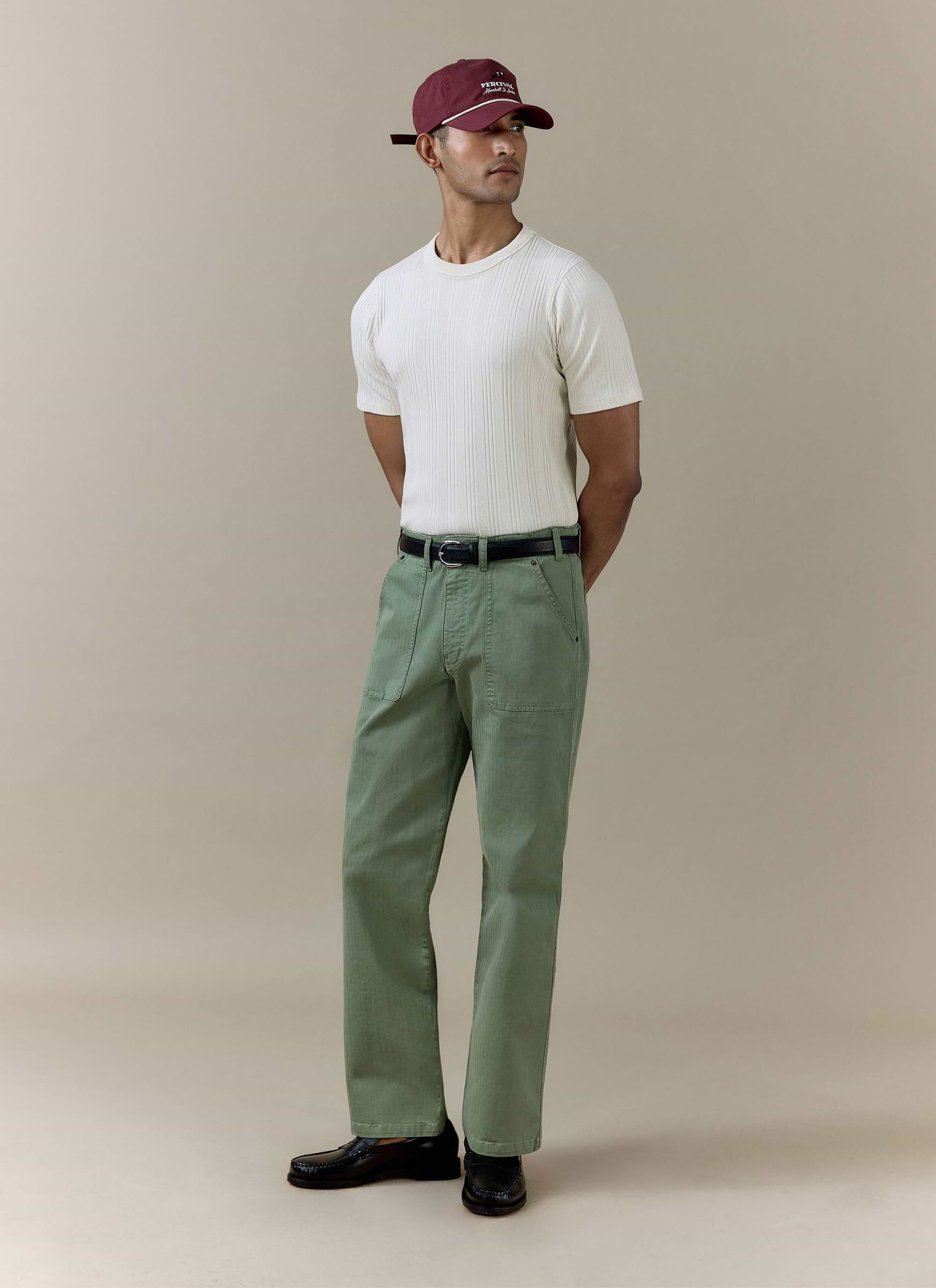 Cream Percival Leon Ribbed T Shirt in organic cotton, styled on a model with green trousers and a maroon baseball cap.