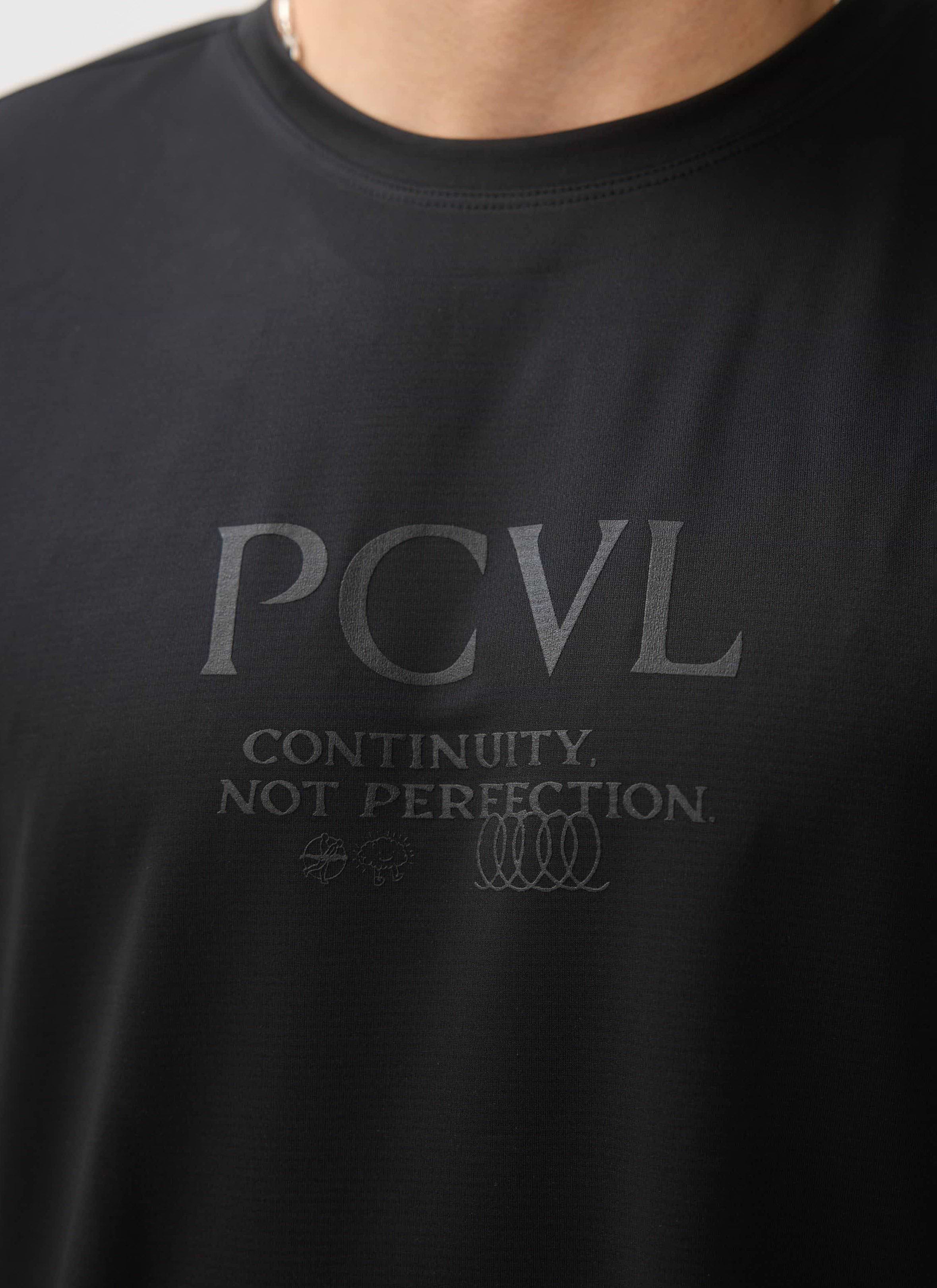 A close-up on the chest of a model wearing the black PCVL Long Sleeve Performance Top by Percival, showing the tonal graphic.