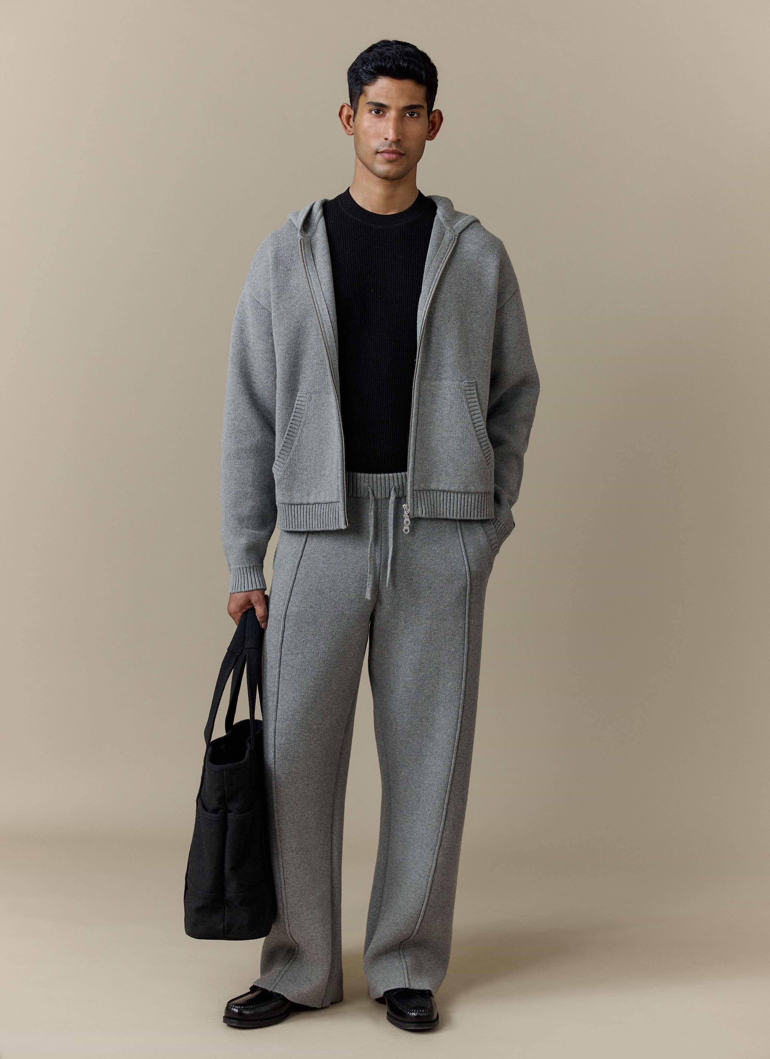 A model wears the Percival Chronicle Knitted Straight Leg Trackpant in grey, styled with the matching zip-up hoodie.