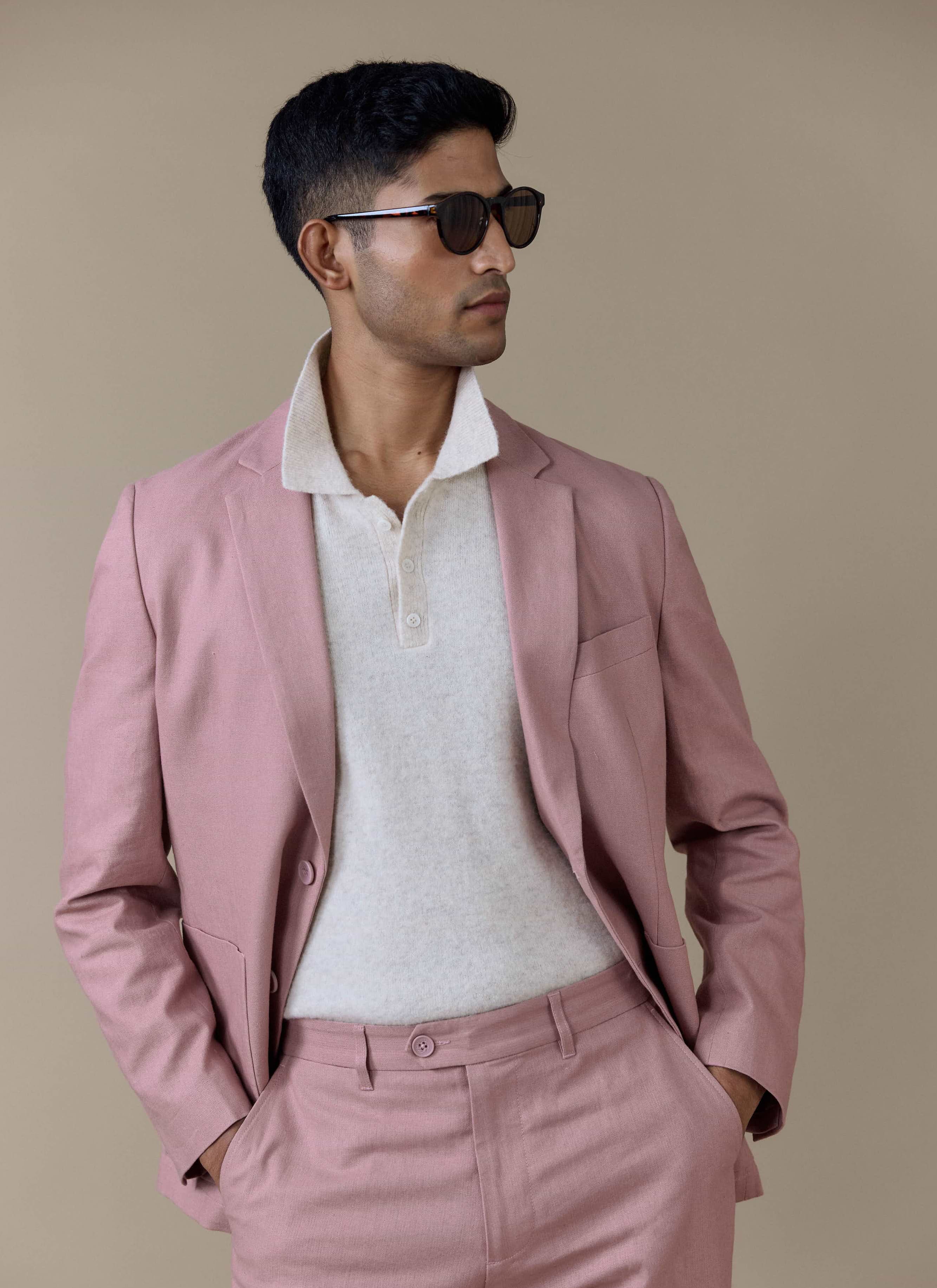 Tailored Dusty Pink linen blazer by Percival, worn by a model with matching trousers and a cream knitted polo.