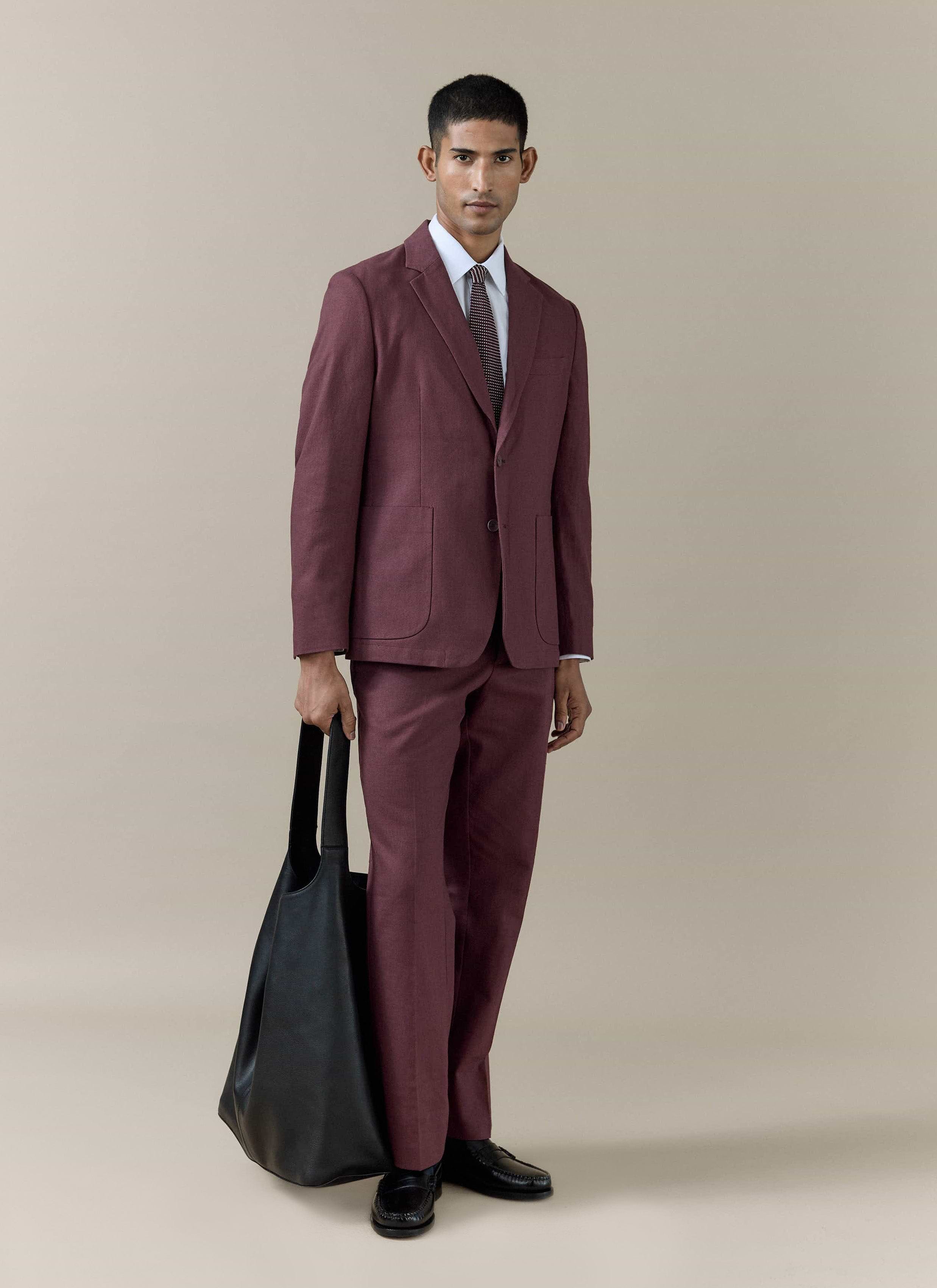 Model wears the merlot Percival Tailored Linen Blazer and matching trousers, styled with a black tote bag.