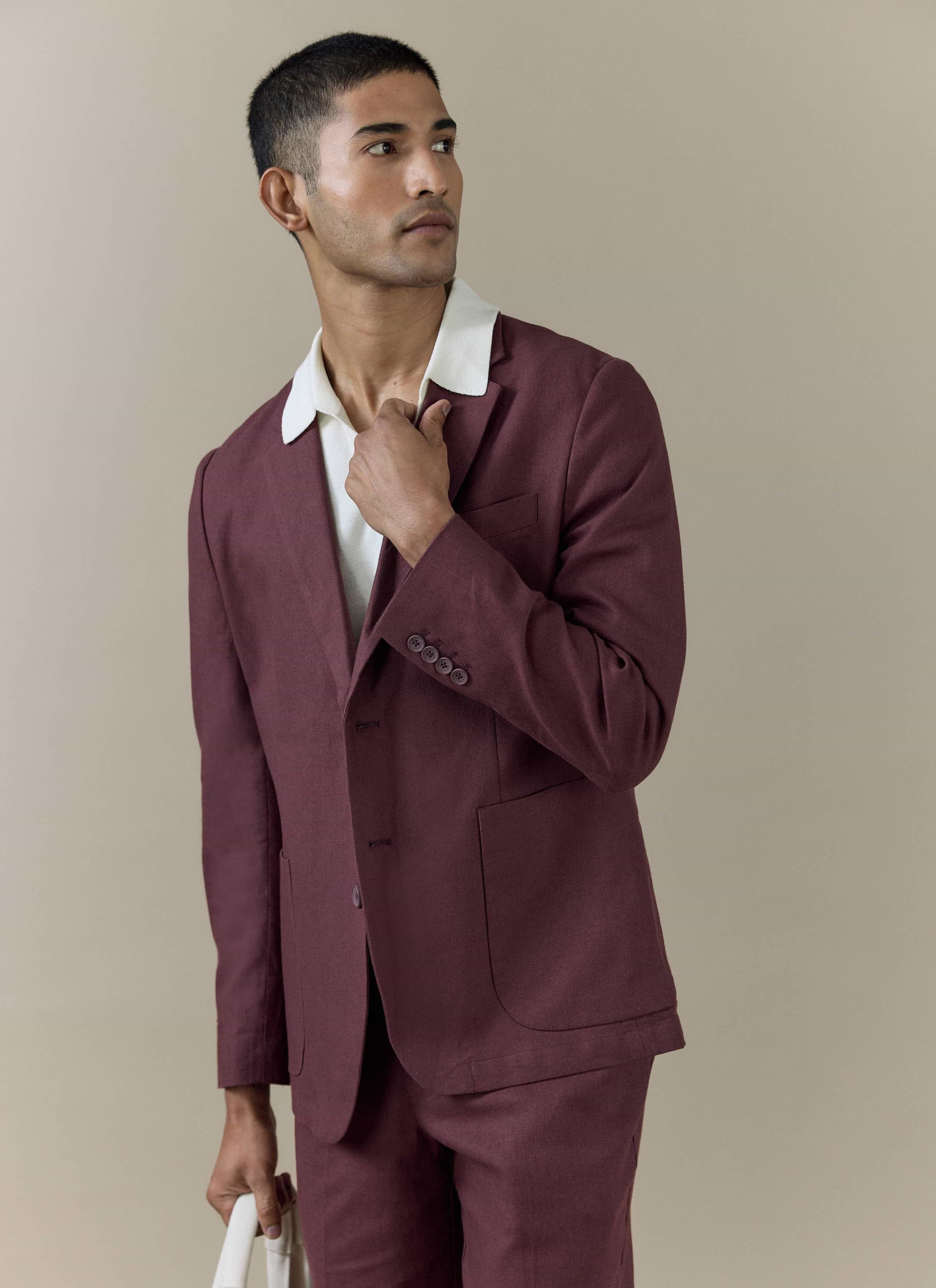 A model wearing the Percival tailored linen blazer in rich merlot burgundy, styled over a white collared knit shirt.