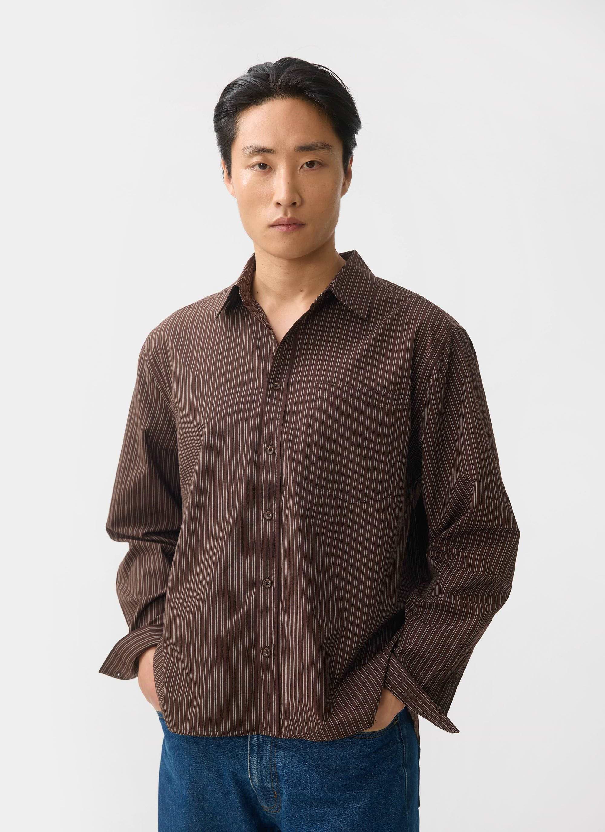 A man models the Percival Clancy Striped Long Sleeve Shirt in brown against a simple white studio background.