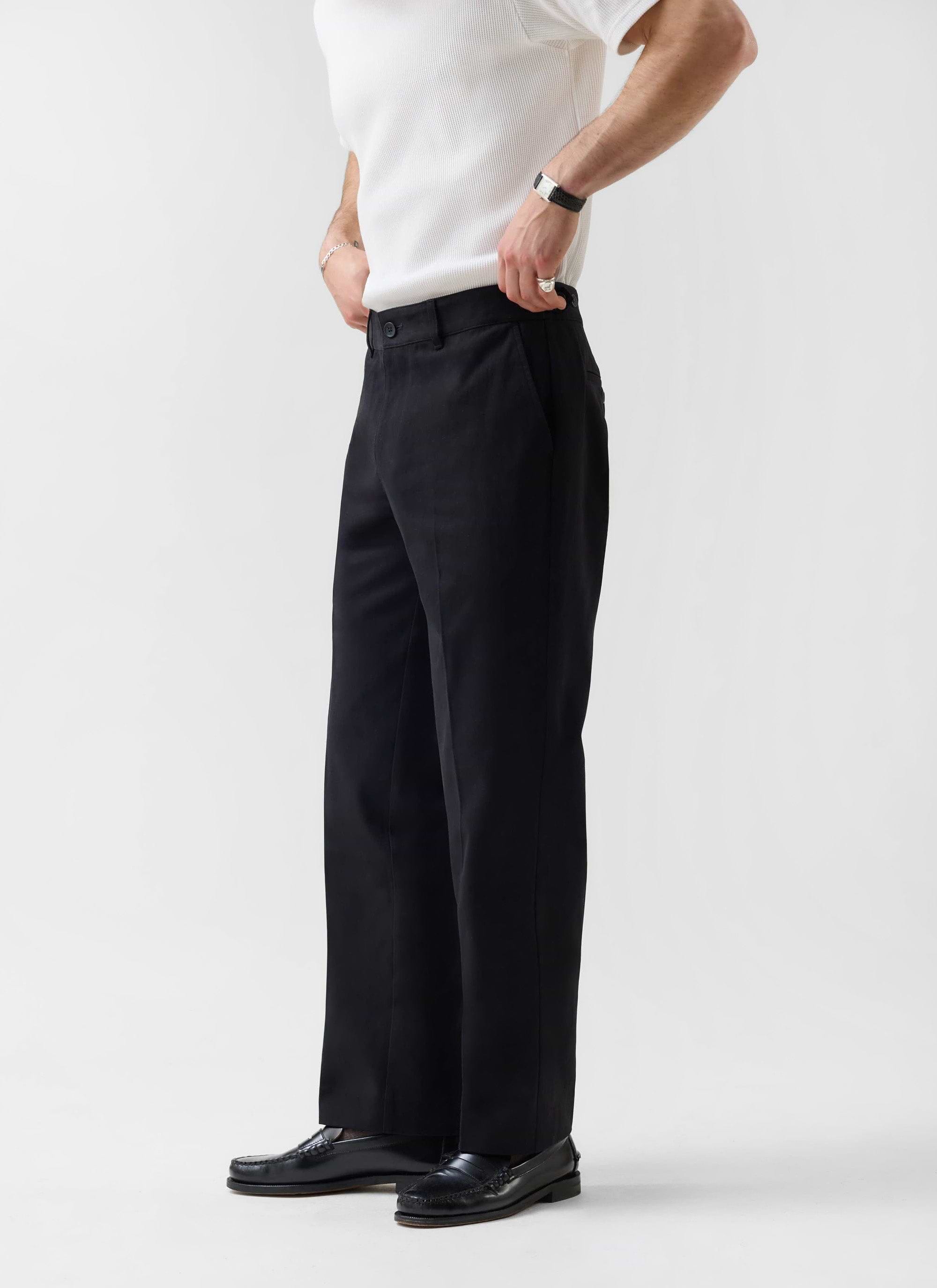 A model wears the black Straight Leg Chino from Percival, styled with a white ribbed top and black leather loafers.