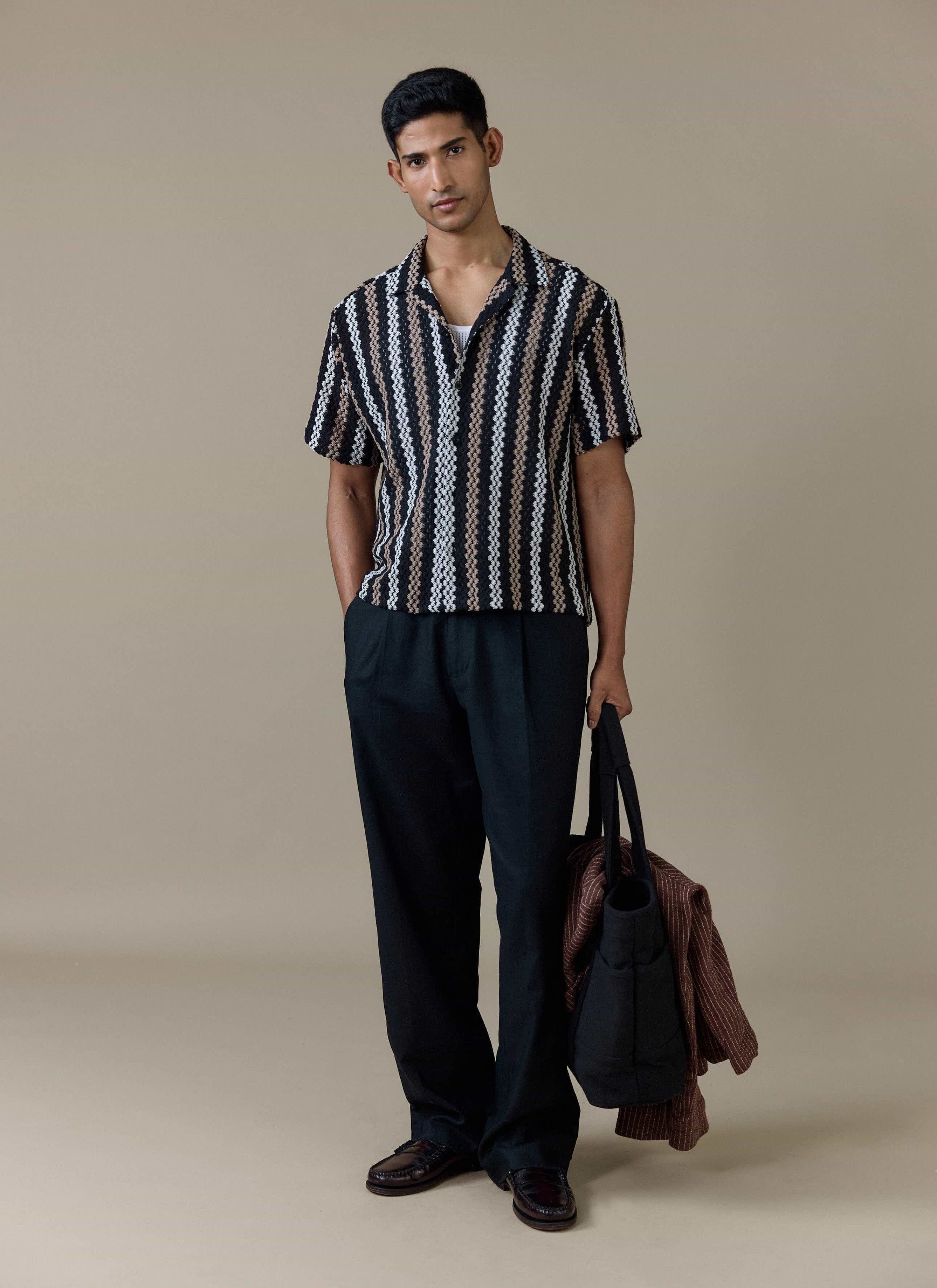 A model wears the Percival Wade Crochet Boxy Shirt in black with vertical stripes, styled with black trousers.