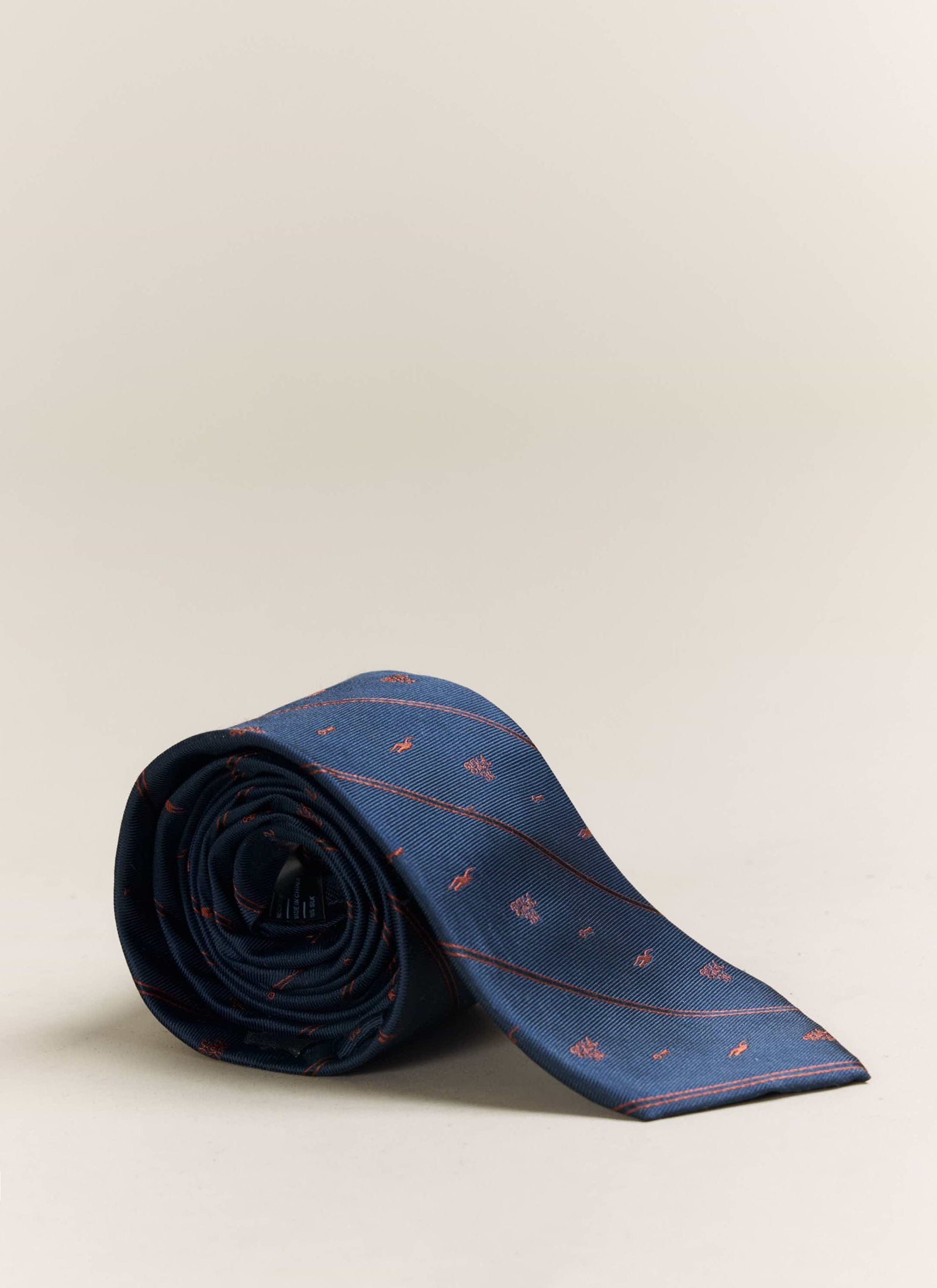 A studio shot of the Percival x Brighton & Hove Albion F.C. navy silk tie, rolled to display the orange jacquard pattern.