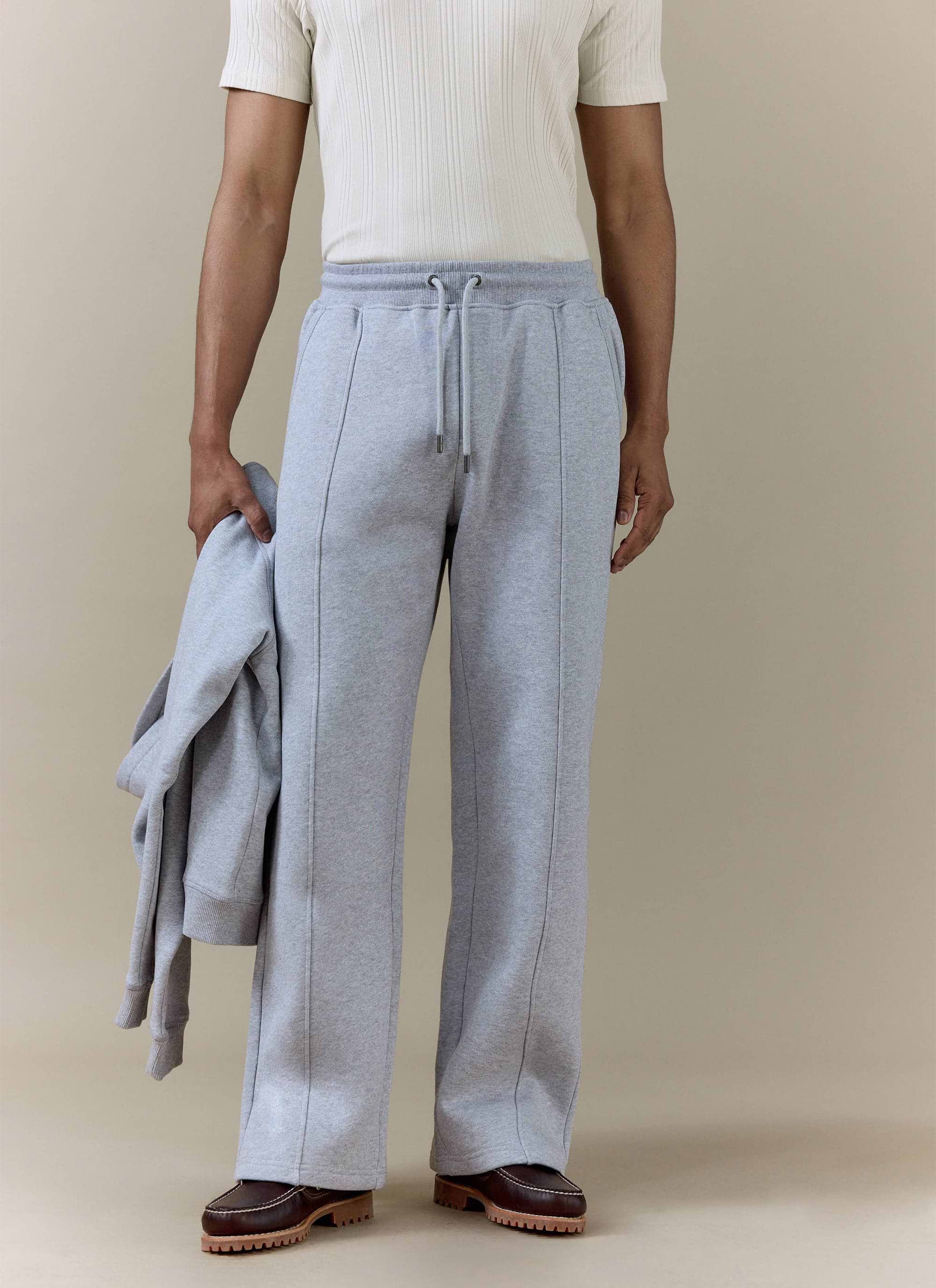 Model wearing Percival grey cotton jersey Chronicle Straight Leg Trackpants, featuring central seam detailing.