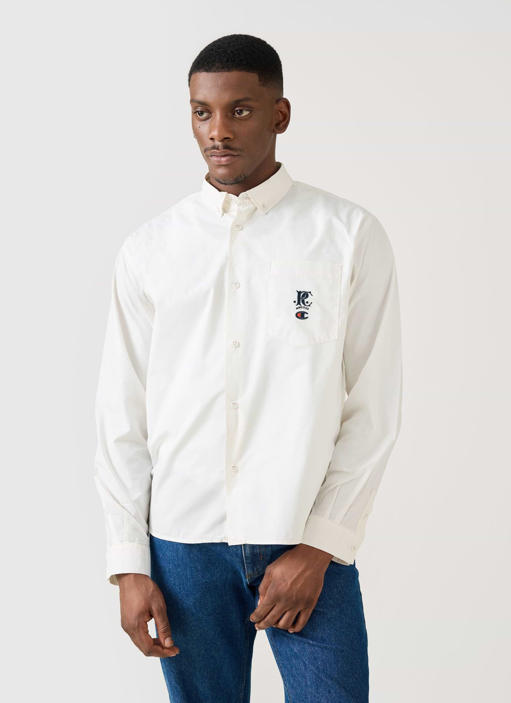 A model wears the Champion x Percival Relaxed Oxford Shirt in ecru against a plain studio background.