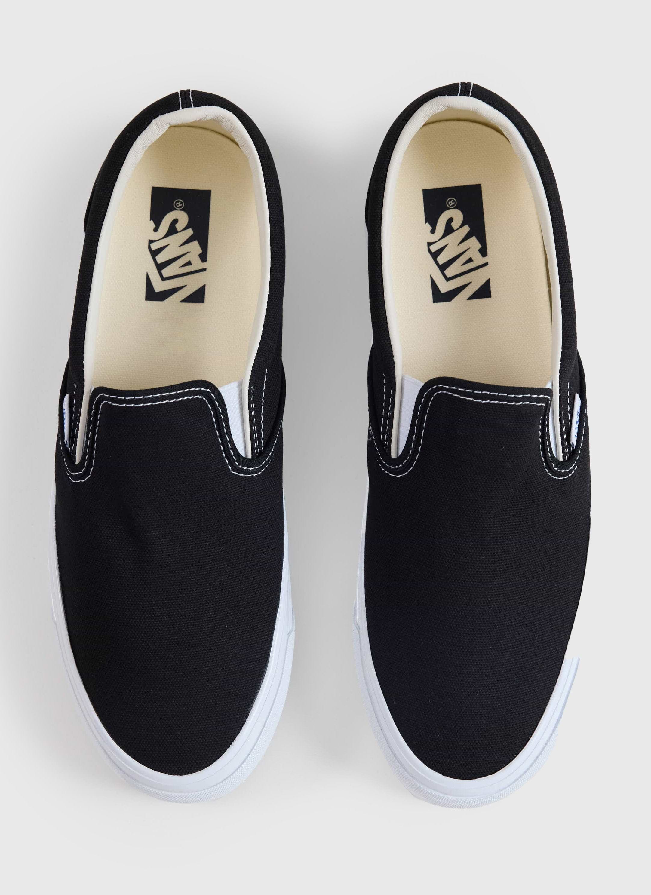 Top-down view of the Vans Slip-On Reissue 98 in black canvas from Percival, featuring white contrast stitching and soles.