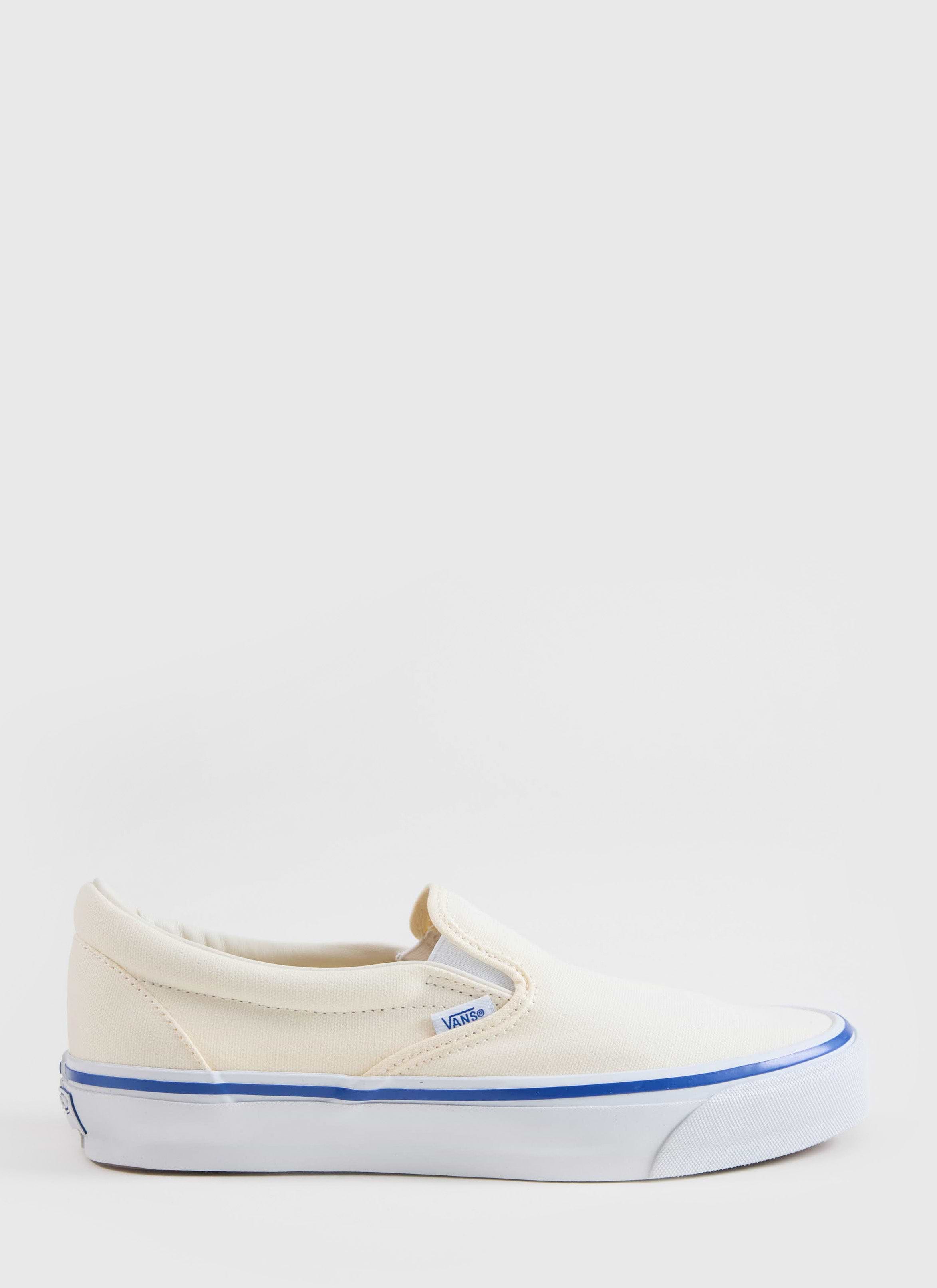 A side profile of the Vans Slip-On Reissue 98 Shoes in off white canvas from Percival, featuring a blue foxing stripe.
