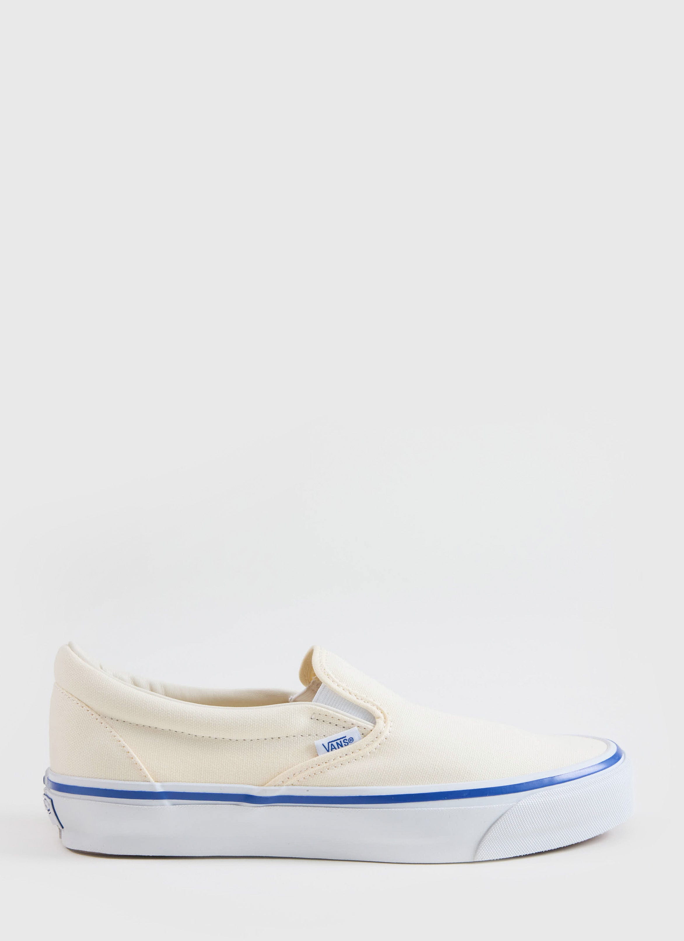 A side profile of the Vans Slip-On Reissue 98 Shoes in off white canvas from Percival, featuring a blue foxing stripe.