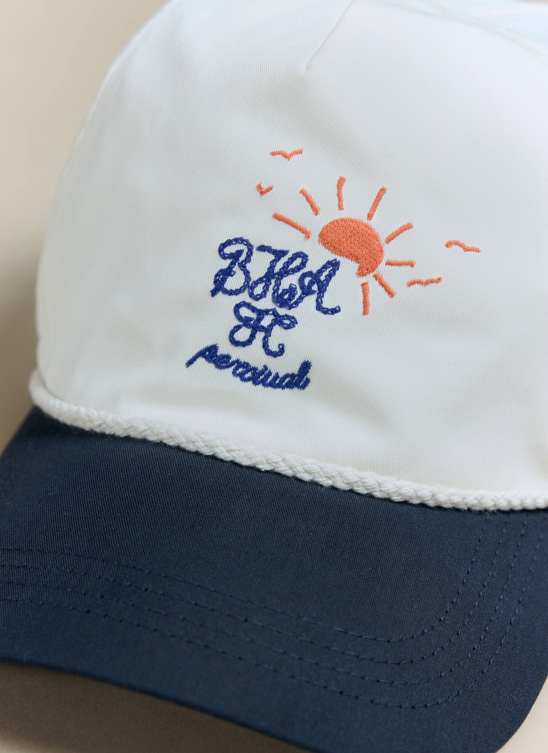 A close-up of the collaborative embroidery on the cream Percival x Brighton & Hove Albion F.C. trucker cap.