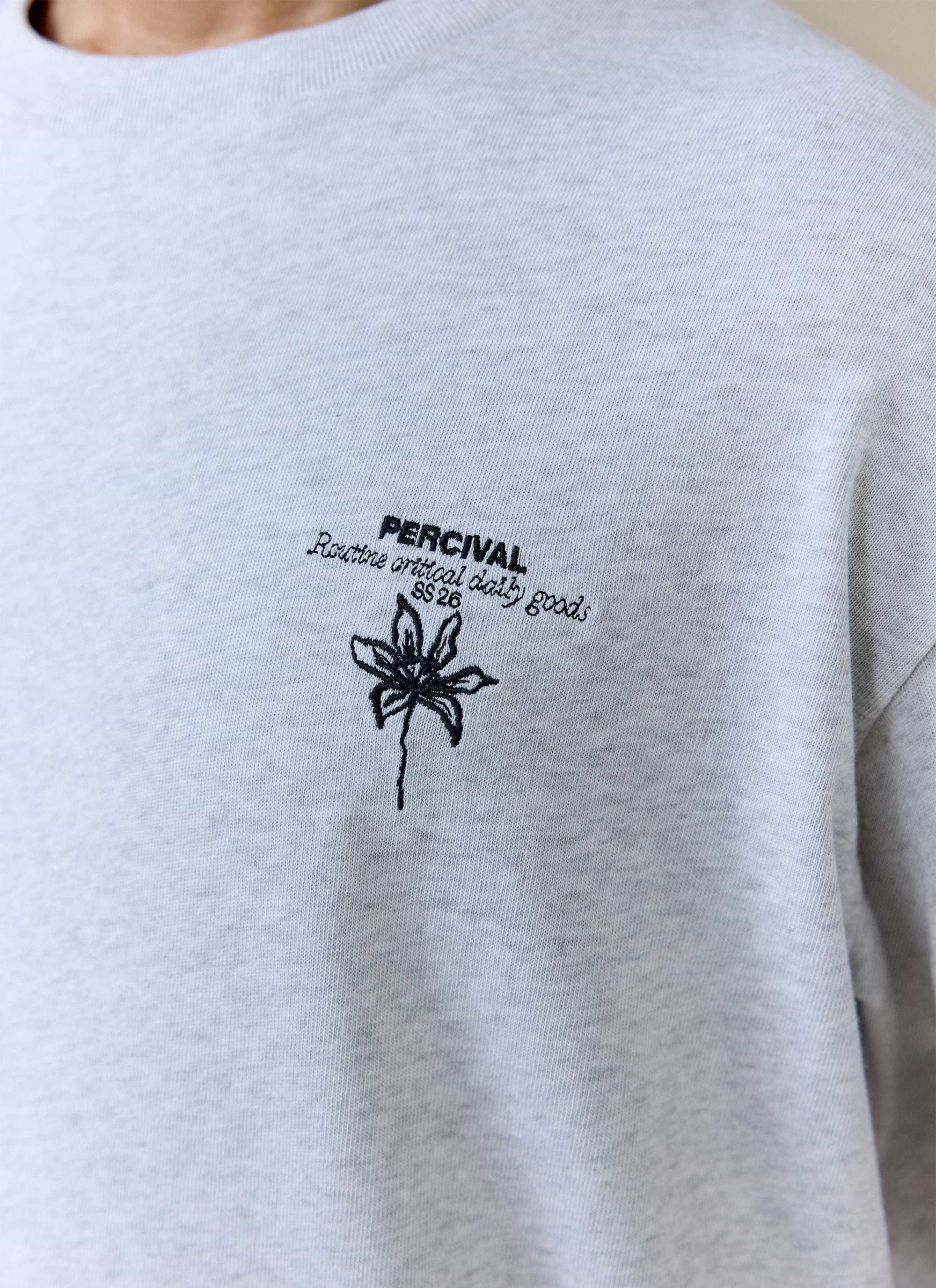 A close-up of the black chest embroidery on the grey organic cotton Percival Melvin Oversized T Shirt.