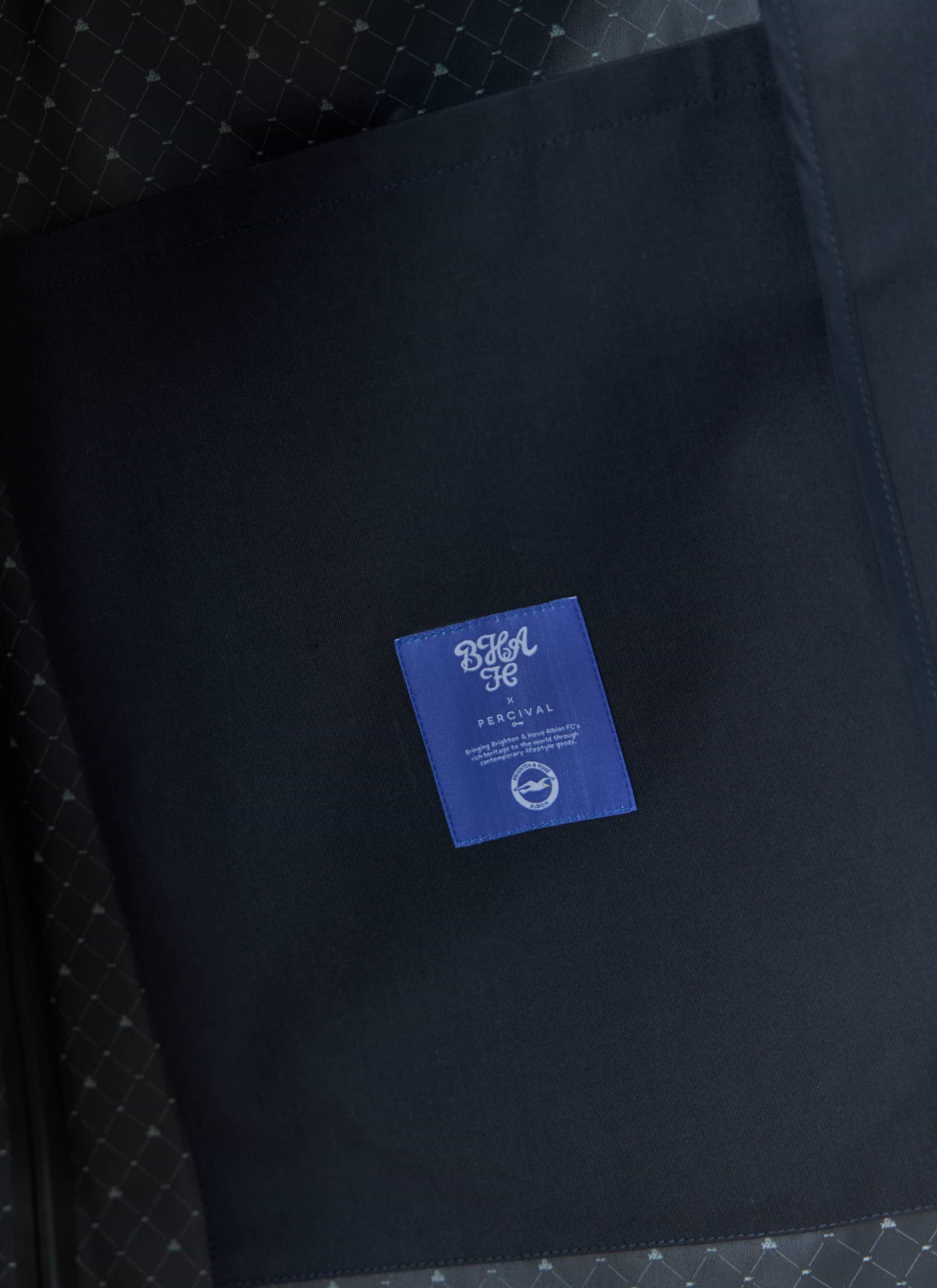 Close-up detail of the Percival x Brighton & Hove Albion FC Sherlock Trench, showing the internal label and patterned lining.