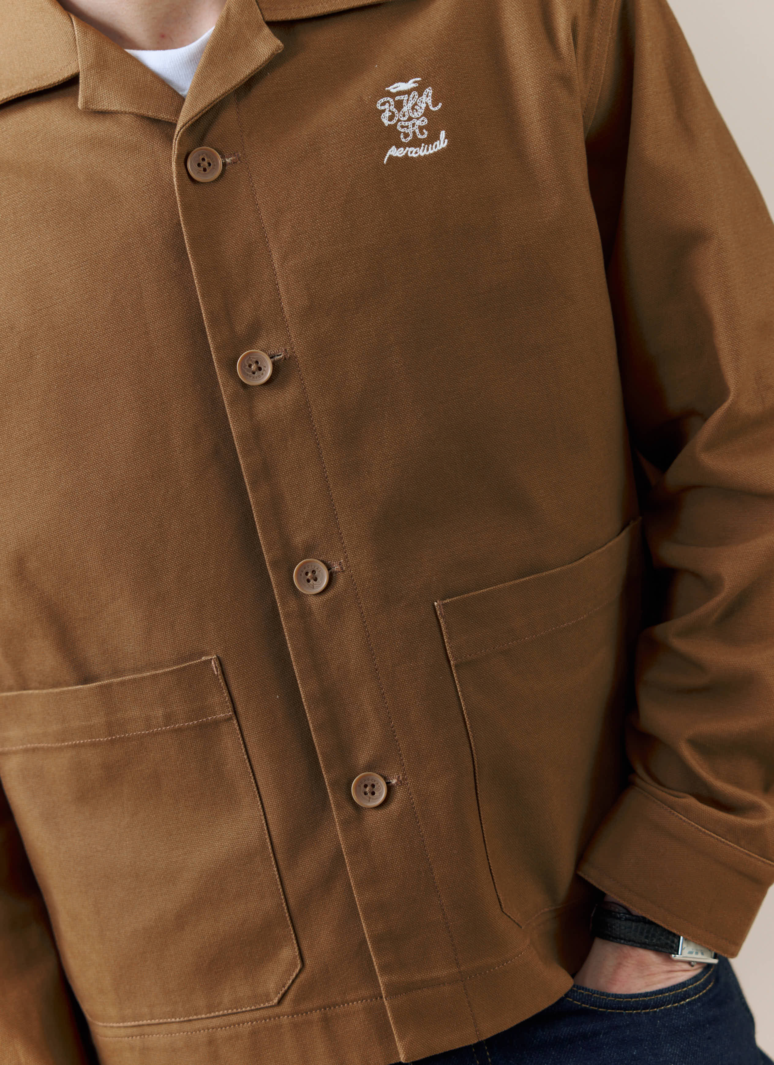 A close-up of the Percival x Brighton & Hove Albion F.C. Canvas Workshirt in brown, showing the chest embroidery.