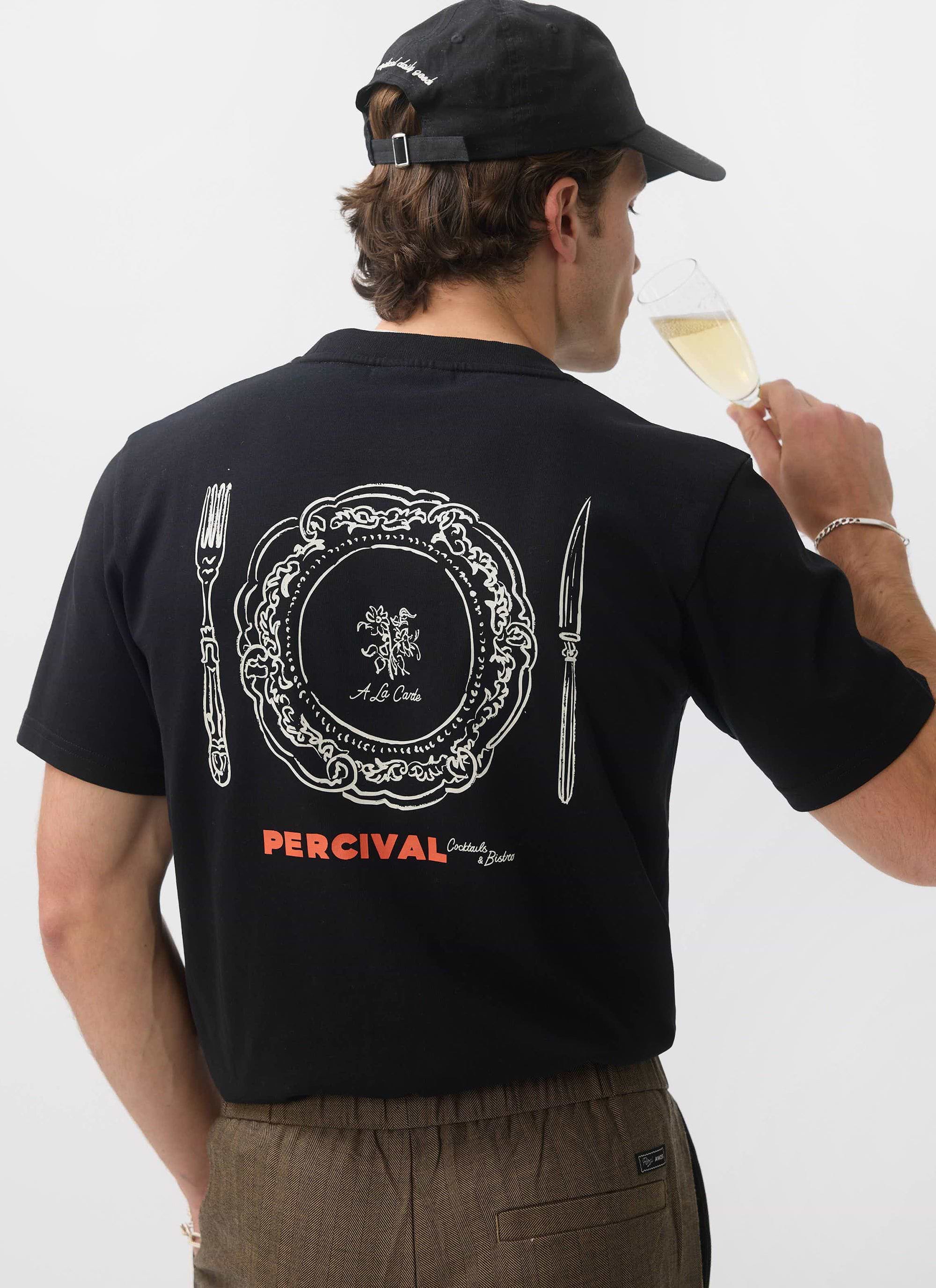 The back of the Percival À La Carte t-shirt in black, worn by a model sipping champagne, displaying the dinner plate graphic.
