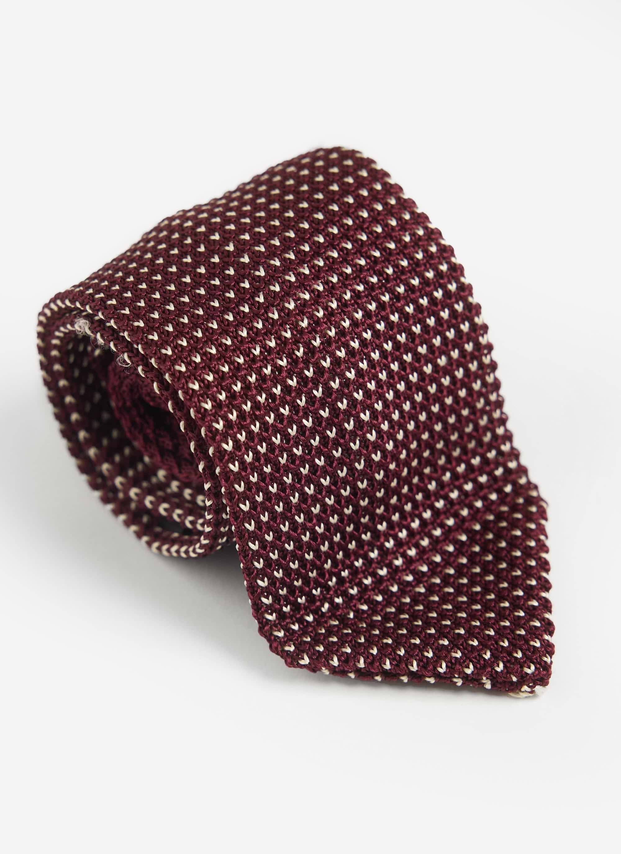 A close-up of the red Percival Birdseye Silk Tie, showing the intricate white and red birdseye knit pattern.