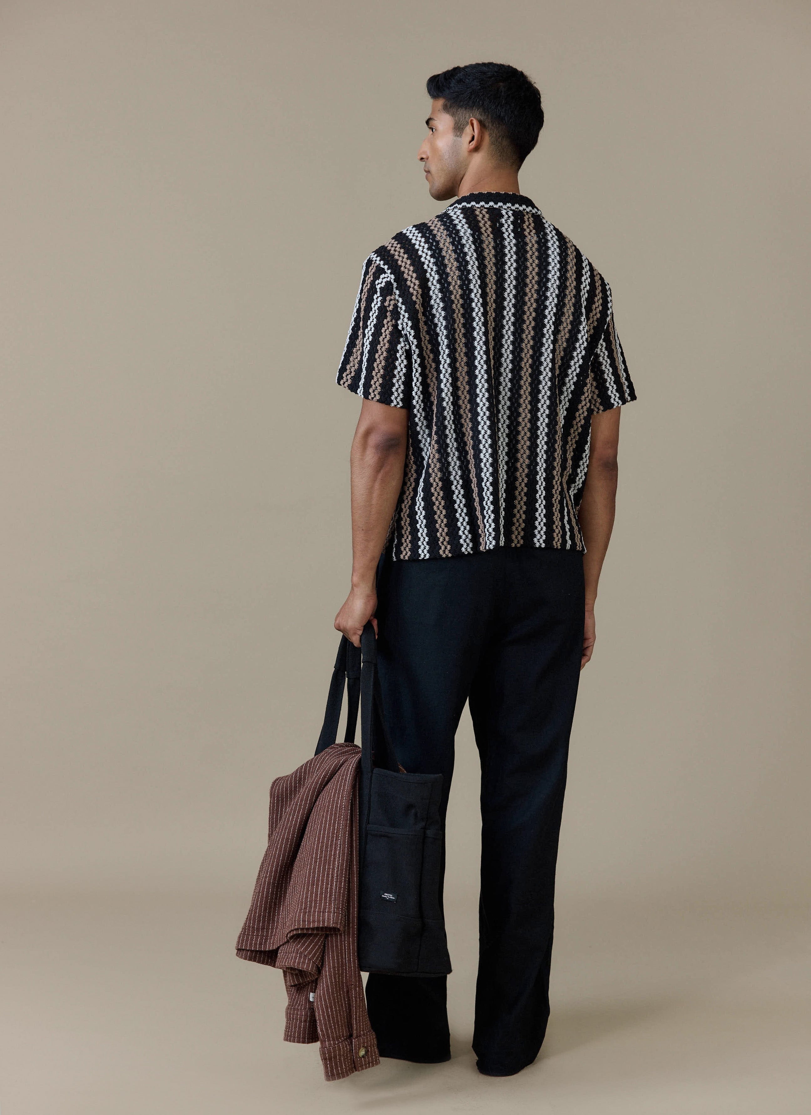 Rear view of a model wearing the Percival Wade Crochet Boxy Shirt in black, showing the textured vertical stripe pattern.