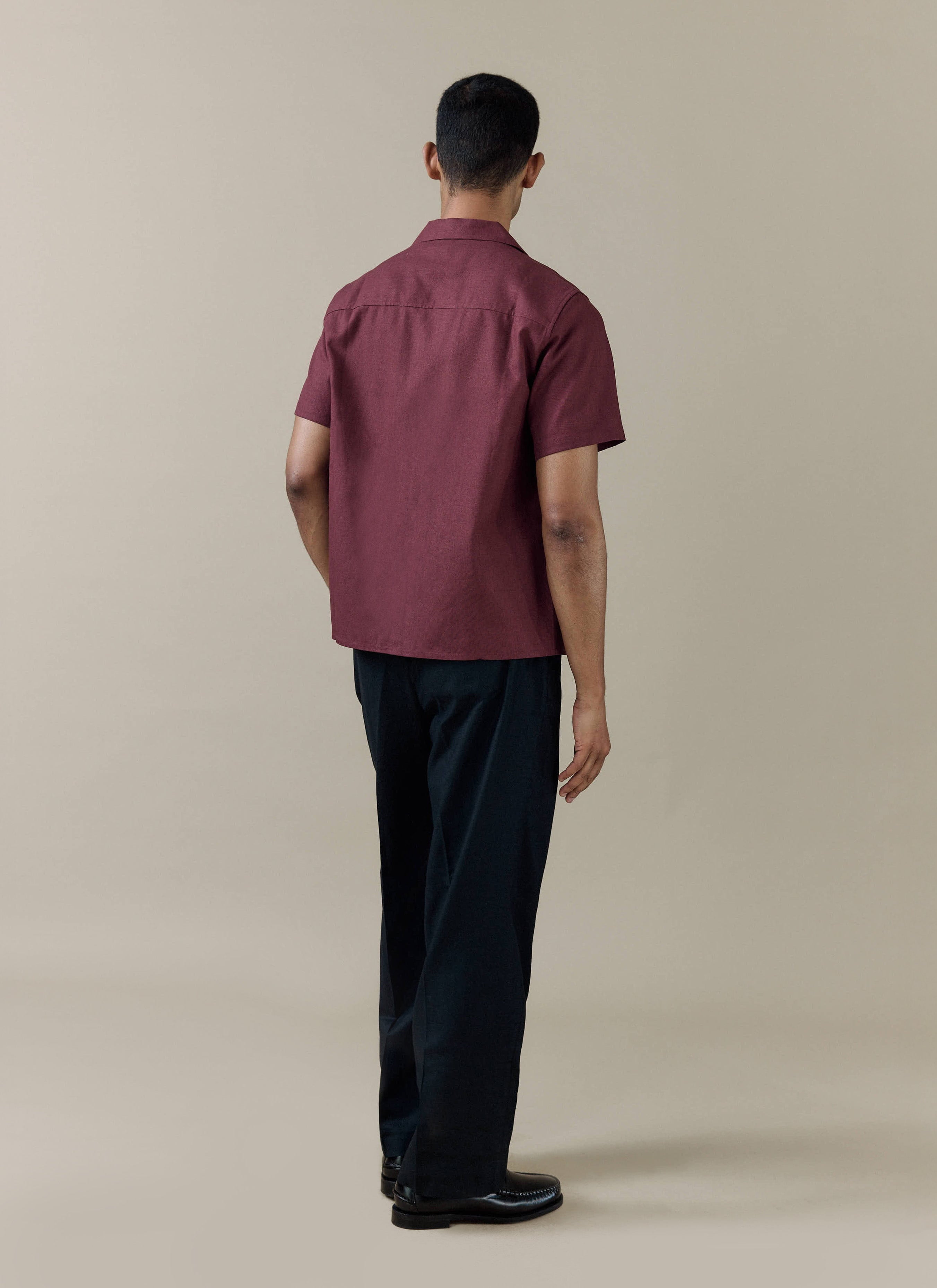 Rear view of the Percival Short Sleeve Cuban Shirt in Merlot linen-cotton blend, styled with black trousers.