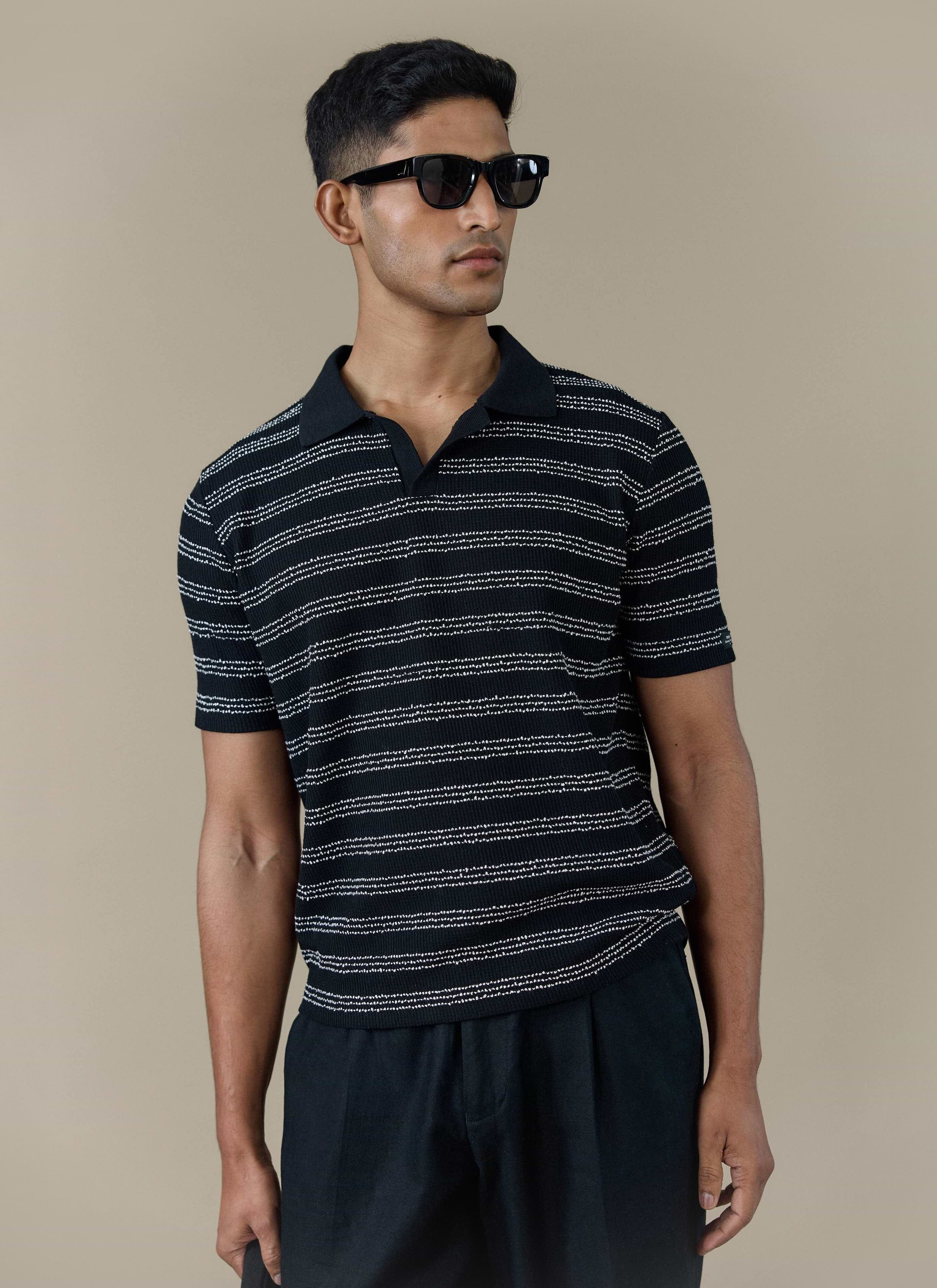 A model wearing the Percival Laurent Polo in black stripe, featuring a boxy fit and textured knit stitch.