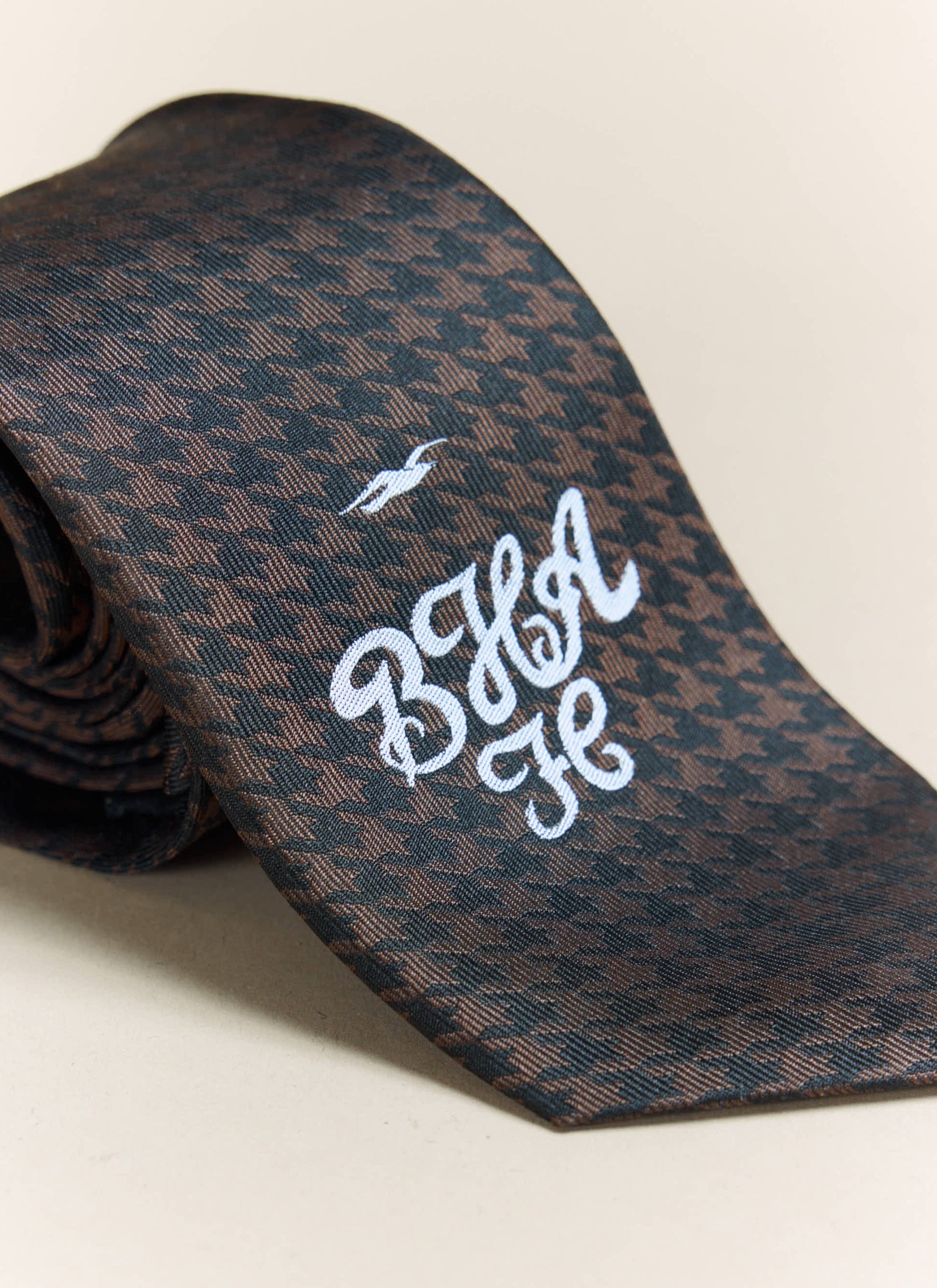 Close-up of the white embroidered Brighton & Hove Albion F.C. crest on the brown houndstooth silk tie by Percival.