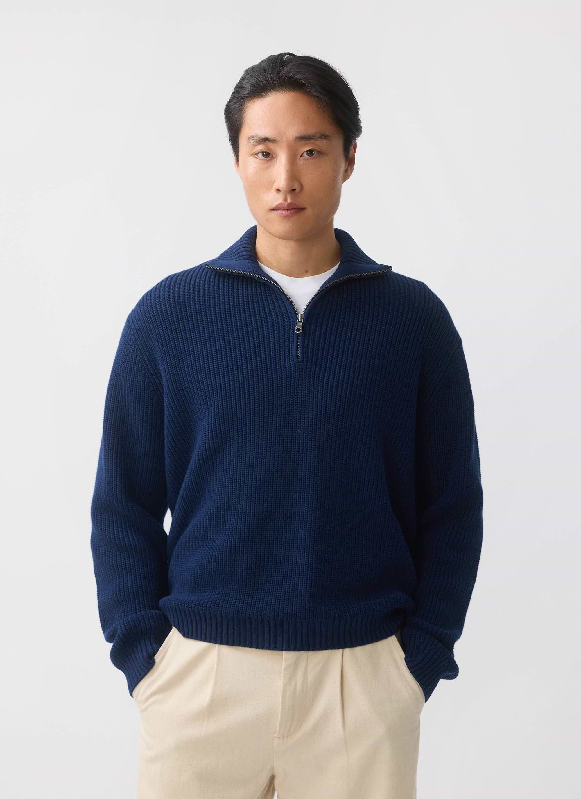 A model wears the Percival Meyer Quarter Zip Fisherman jumper in blue cotton with beige trousers against a white background.