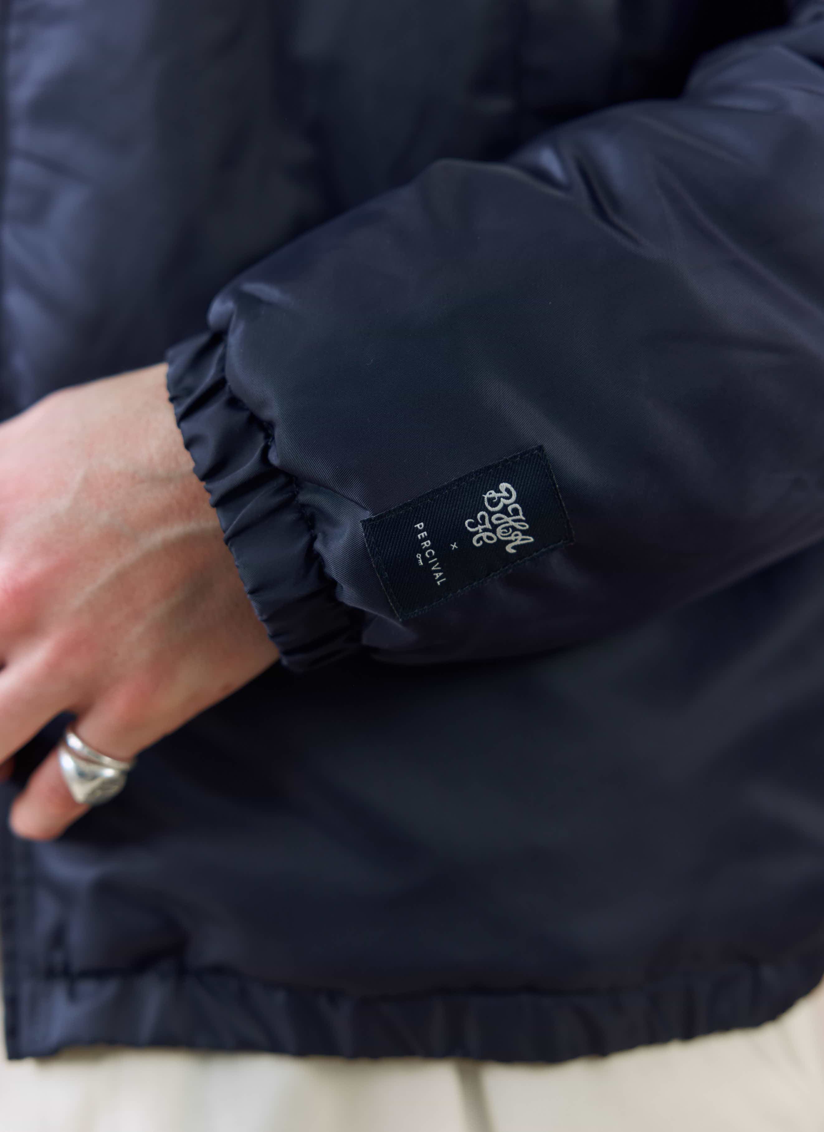 A close-up of the cuff on the navy Percival x Brighton & Hove Albion Coach Jacket, showing the woven collaboration label.