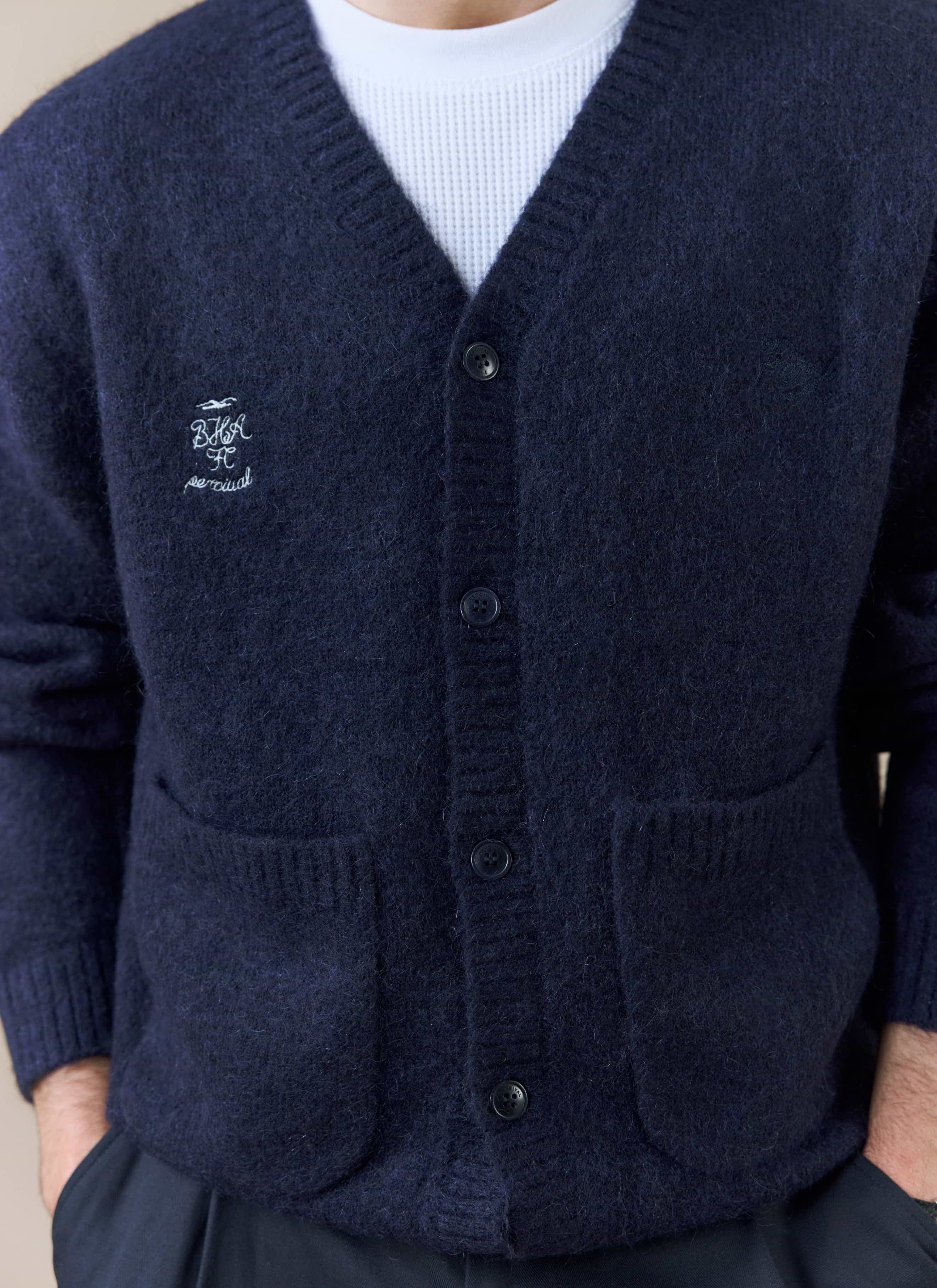A close-up of the white chest embroidery on the navy White Glove Cardigan from the Percival x Brighton & Hove Albion F.C.