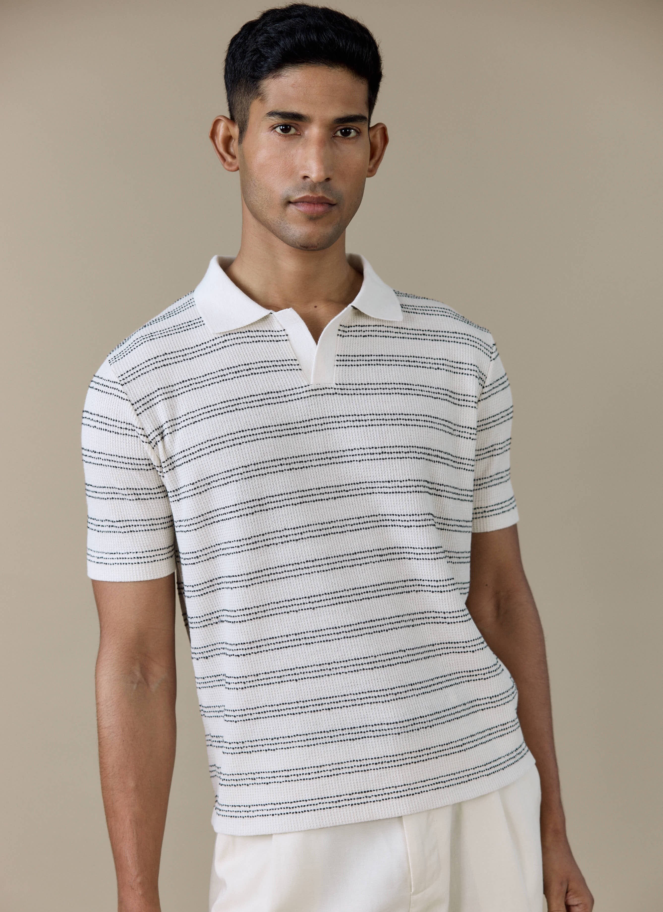 Model wearing the Percival Laurent Boxy Polo in cream, featuring horizontal navy stripes and an open collar.
