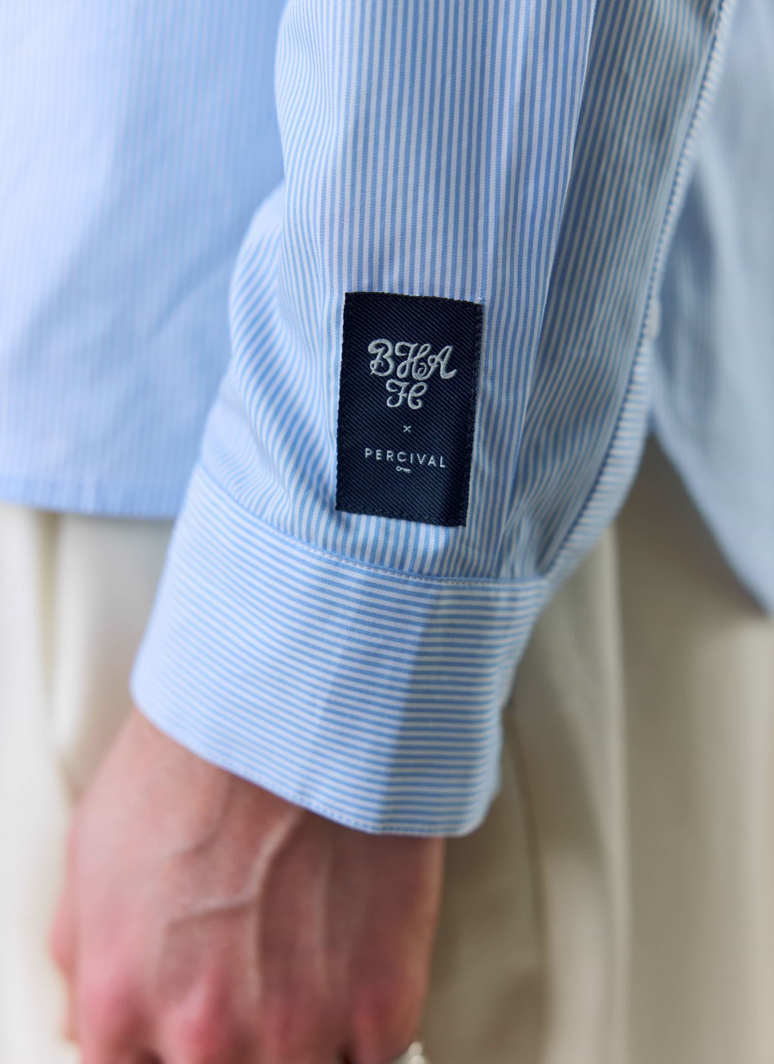 A close-up of the Percival x Brighton & Hove Albion F.C. woven label on the sleeve of the striped Pearce shirt.