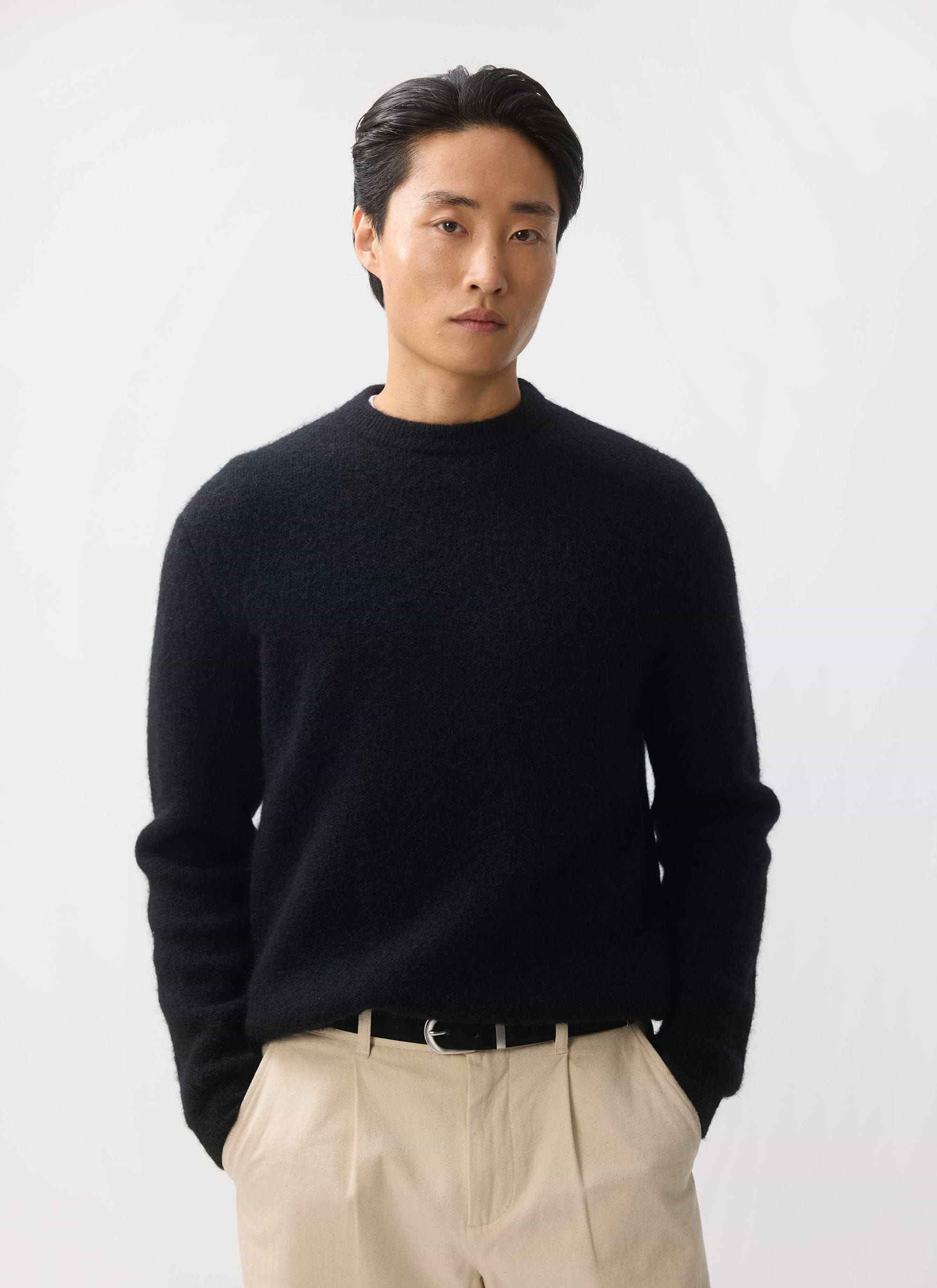 A model wears the Percival White Glove Crew Neck Jumper in black mohair, styled with beige trousers.