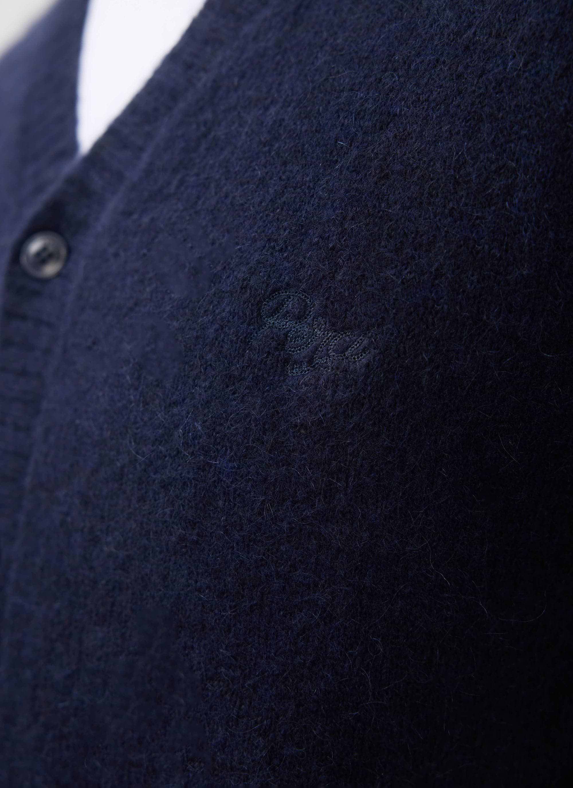 A close-up of the tonal chest embroidery on the navy mohair White Glove Cardigan from Percival.