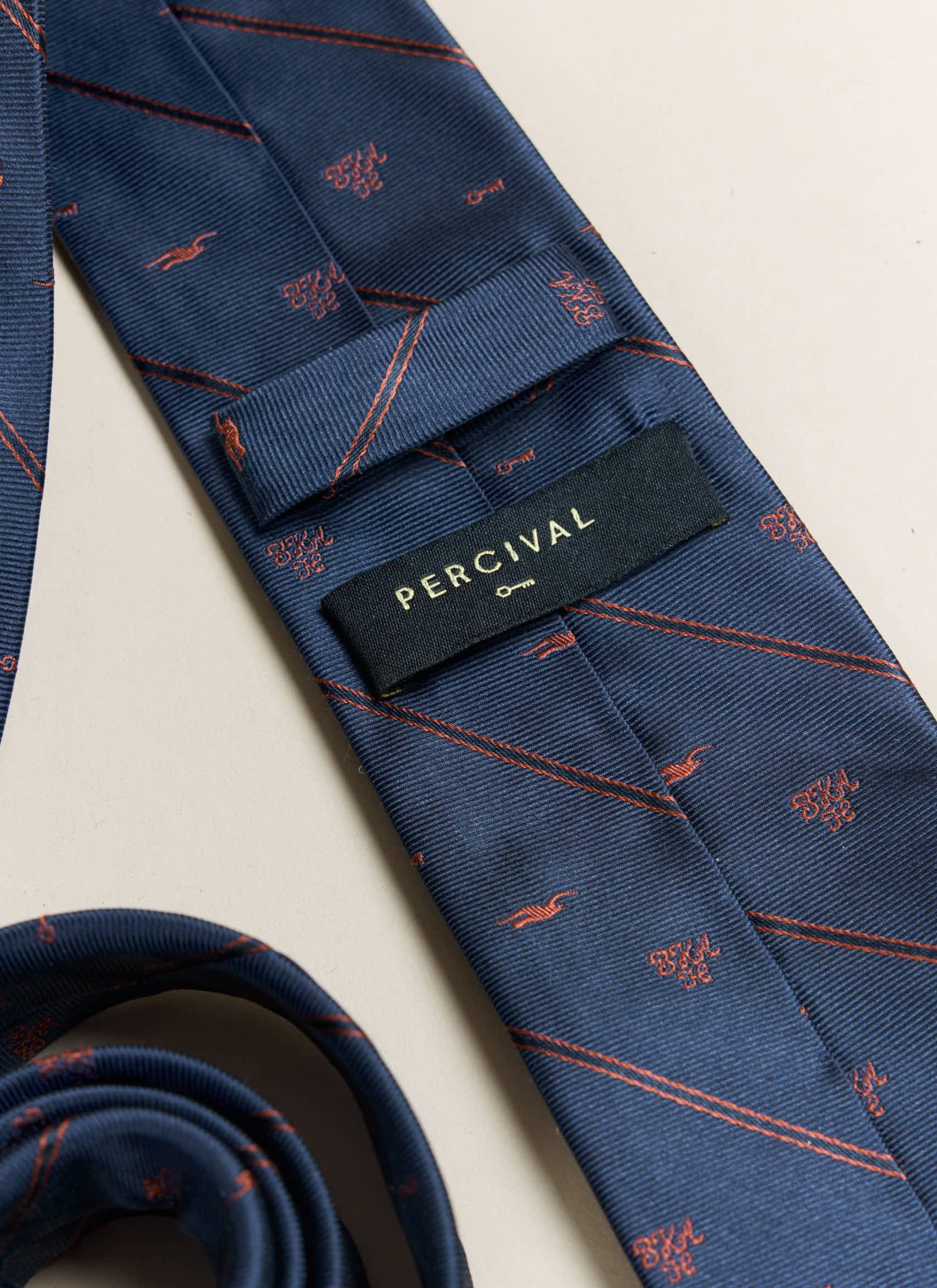 A close-up of the Percival label on the reverse of the navy silk Percival x Brighton & Hove Albion F.C. Jacquard Stripe Tie.
